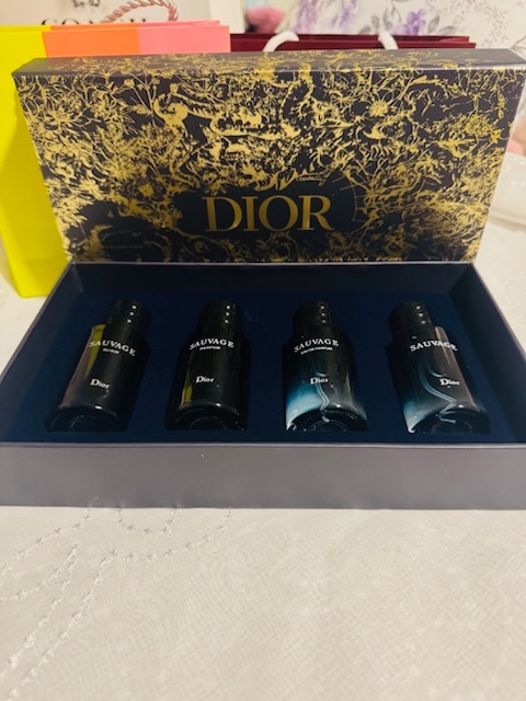 Dior Sauvage mens fragrance gift set featuring four dark blue glass perfume bottles in gold patterned Dior presentation box