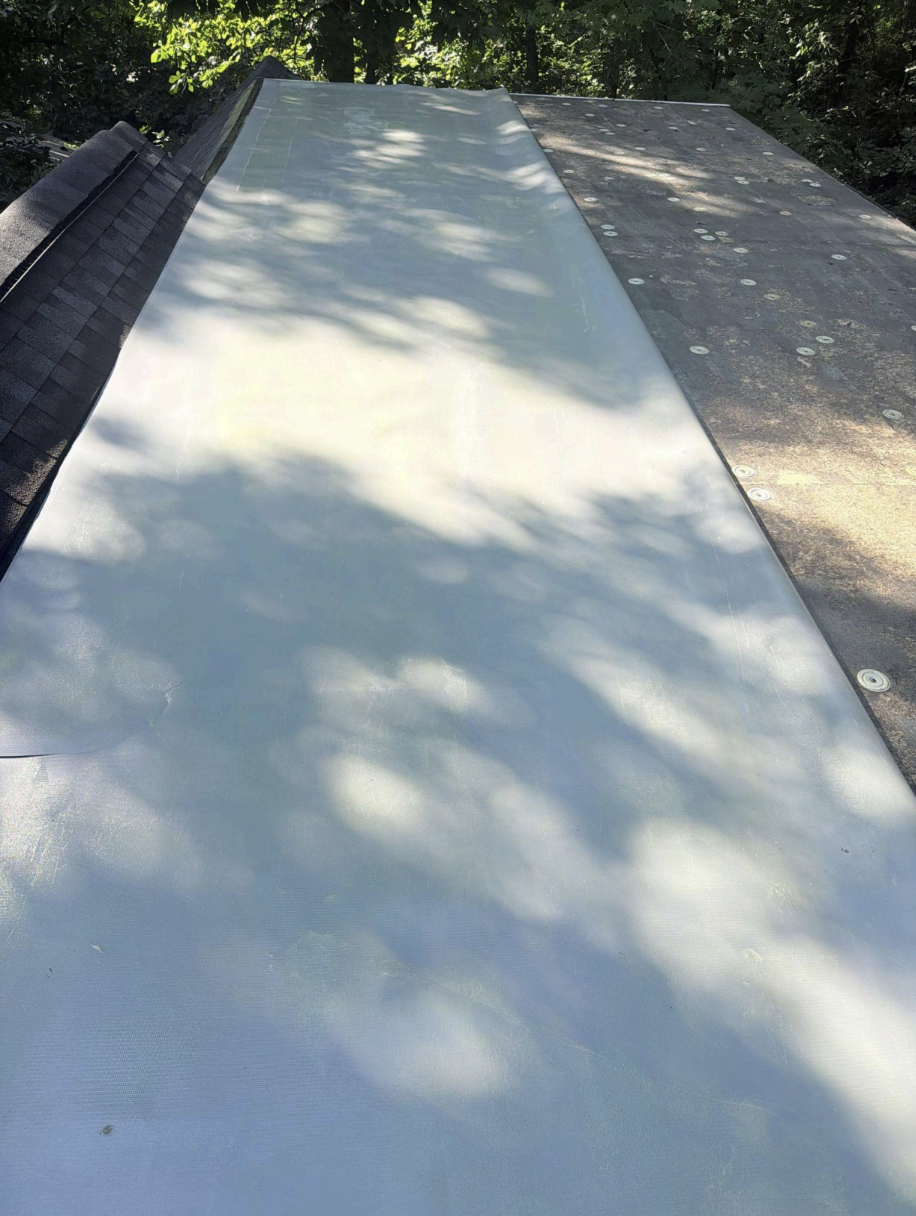 Roofing crew installing synthetic underlayment on residential roof deck in progress