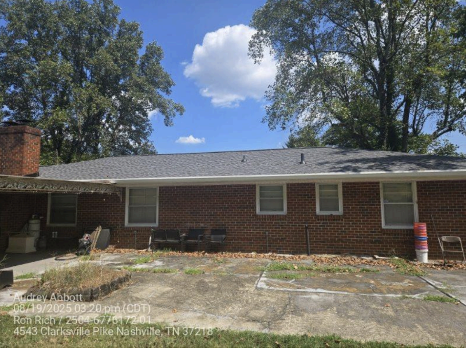 Brick garage with completed shingle roof and Knock on Wood Roofing sign in driveway