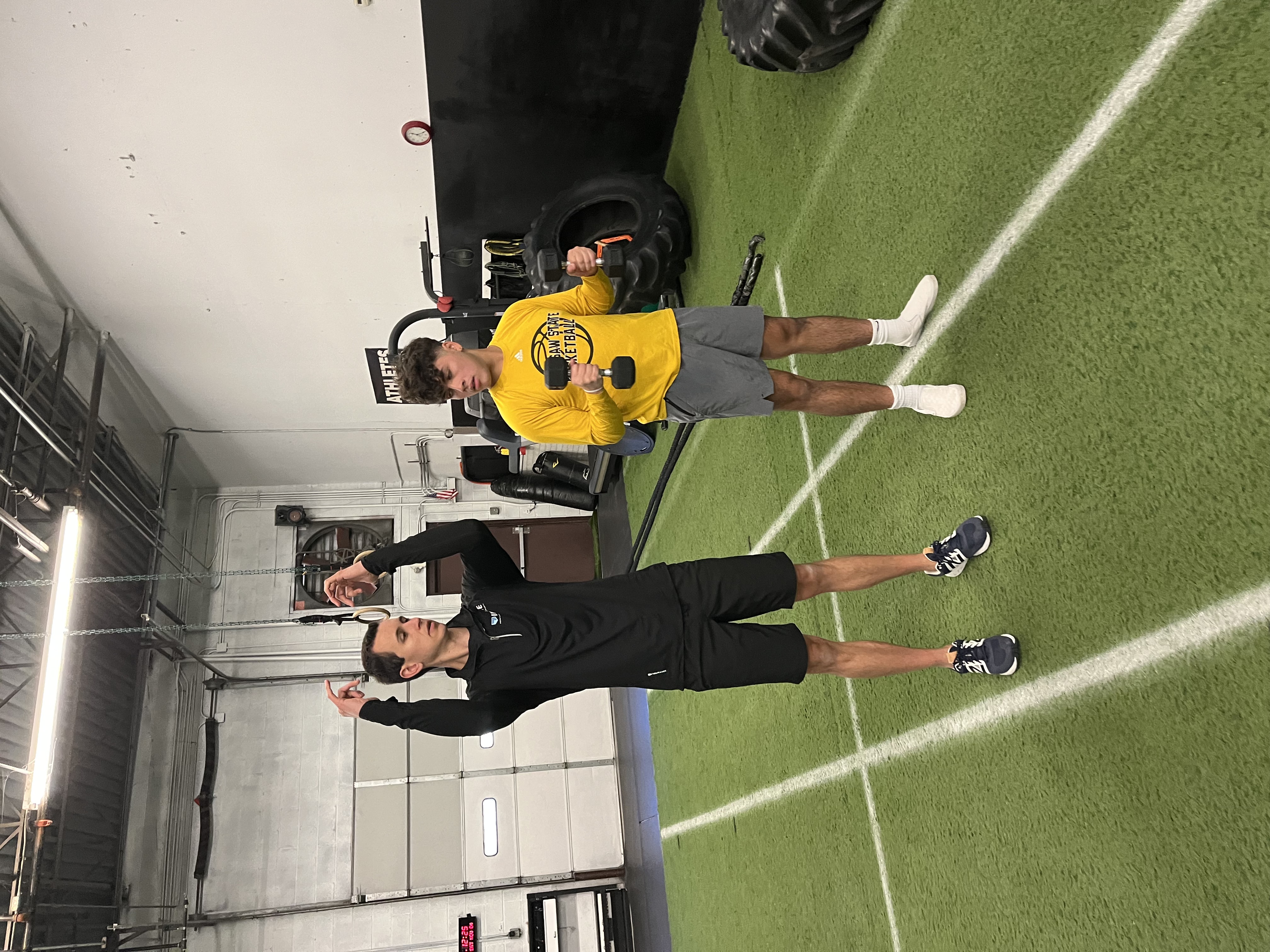 Dr. Caleb Kutsche guiding an athlete during a strength training session in the gym