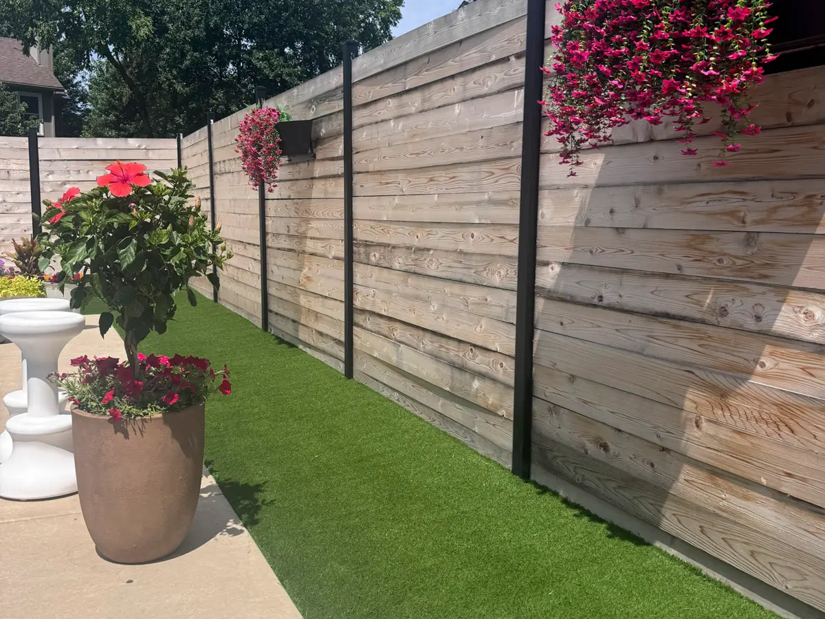 Artificial turf installed in narrow side yard pathway with fence and planters