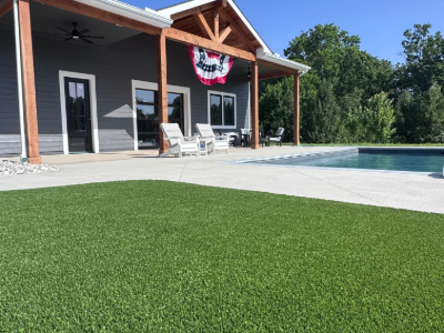 Artificial turf installed beside pool deck and patio house