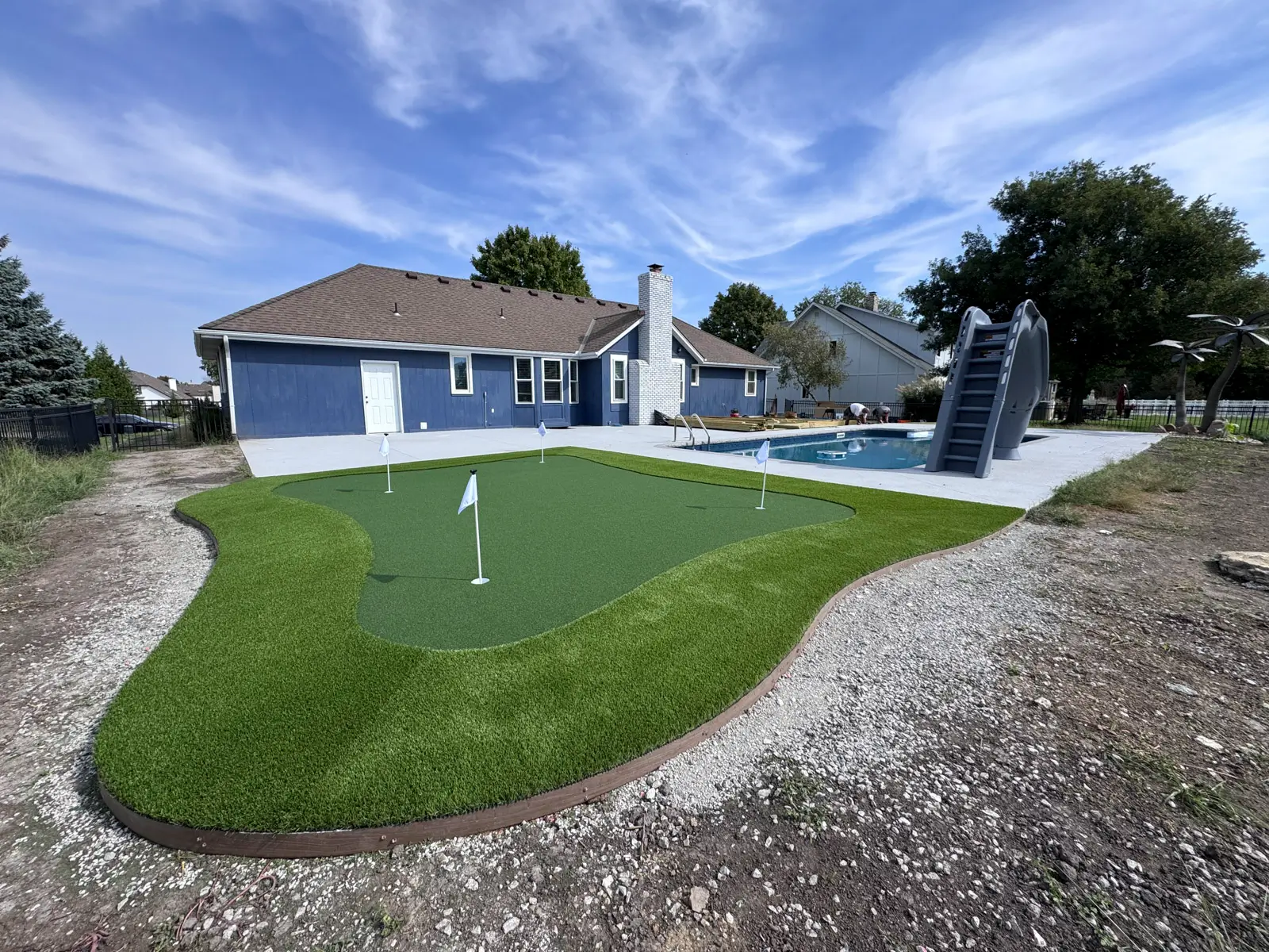 Continuous artificial turf connecting pool, patio, and backyard zones