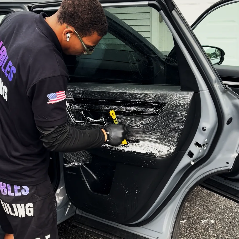 Isaiah detailing interior door panel on a customer vehicle in West Bridgewater MA