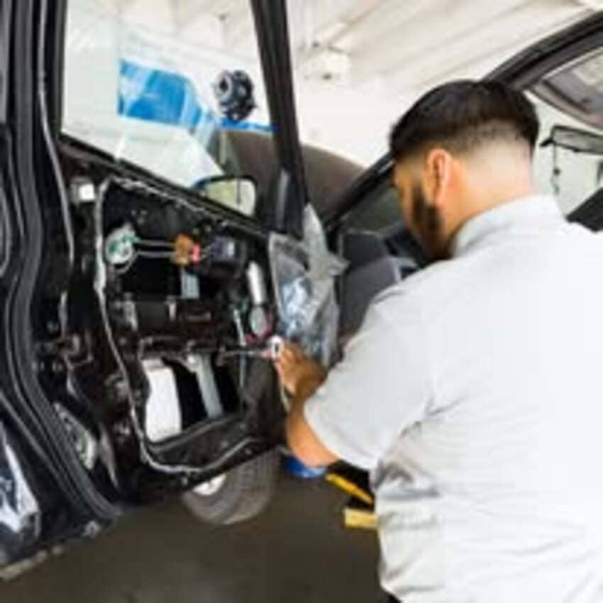 Mechanic working on vehicle door panel repair at Center Cities Automotive