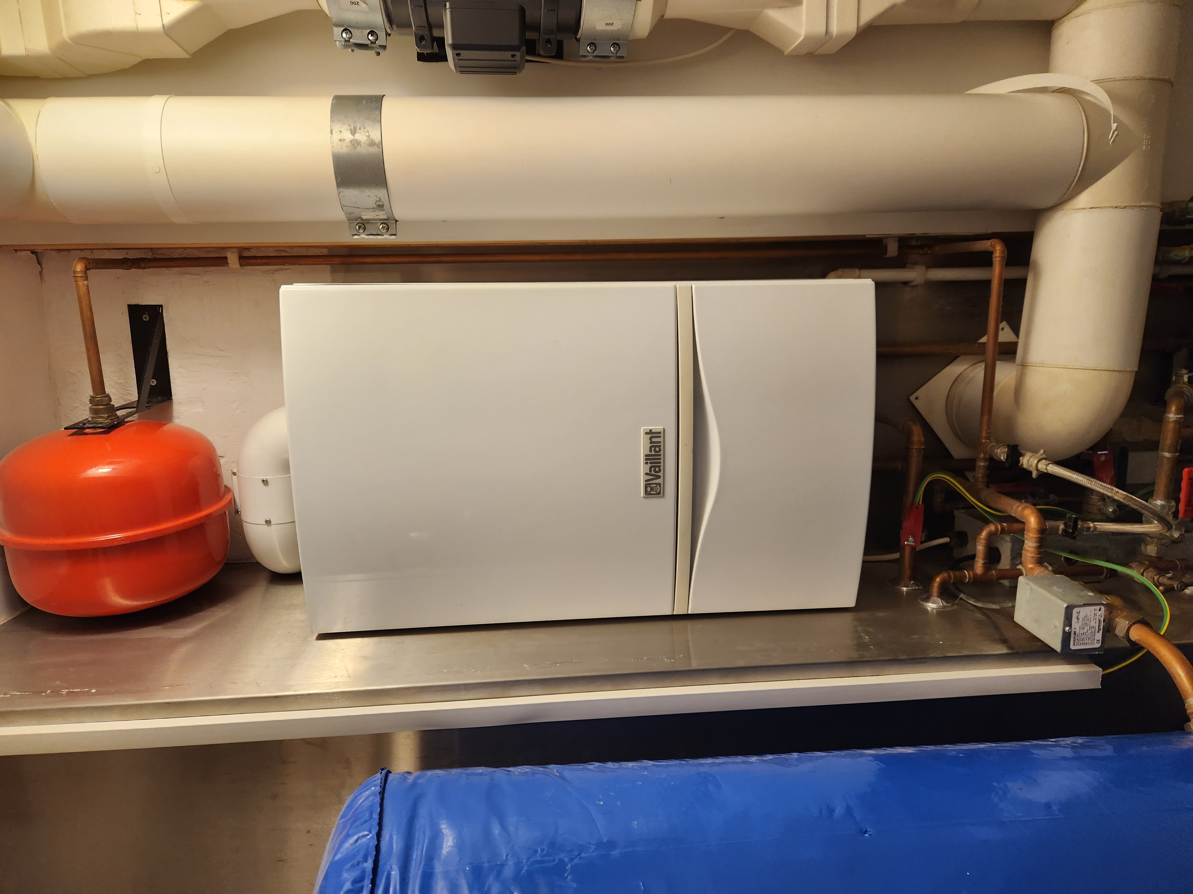 White Vaillant ecoTEC boiler installed alongside a red expansion vessel with neatly arranged copper pipework.