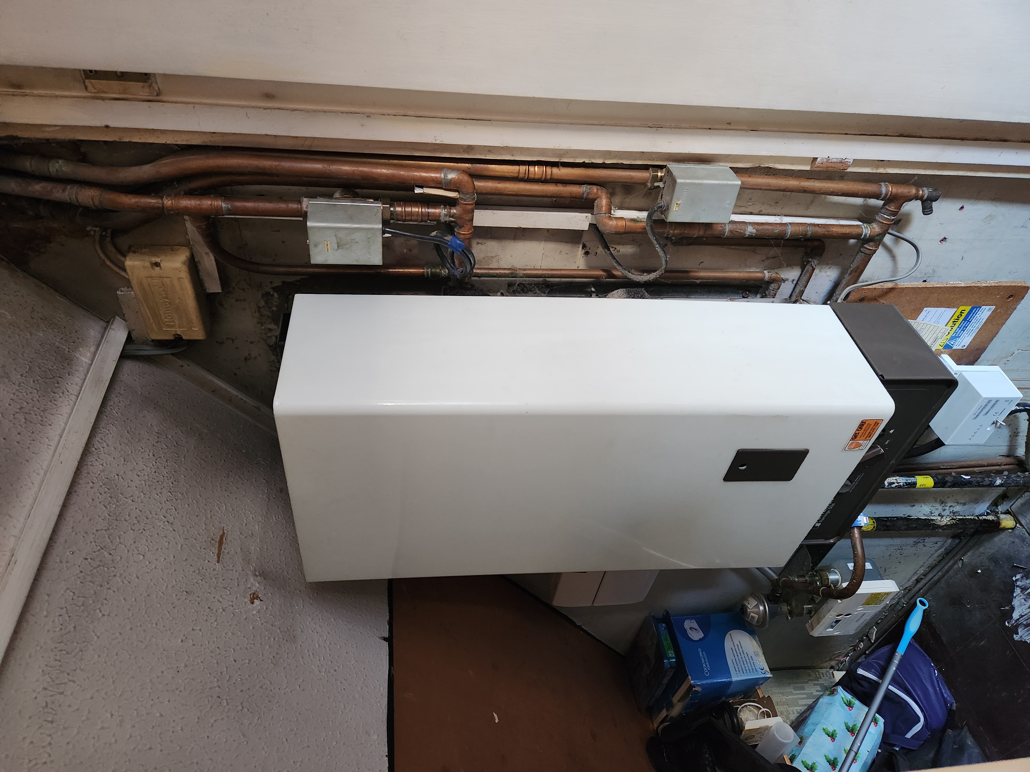 White boiler installed in a utility area with copper pipework and electrical controls.