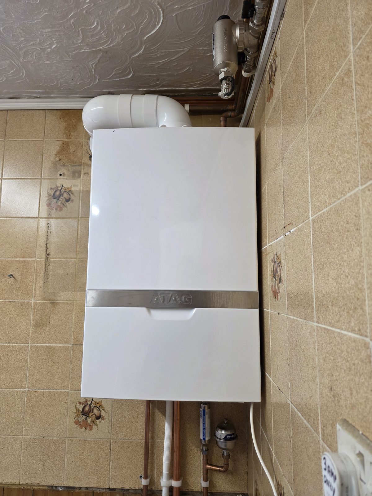 ATAG boiler installed on a tiled wall.