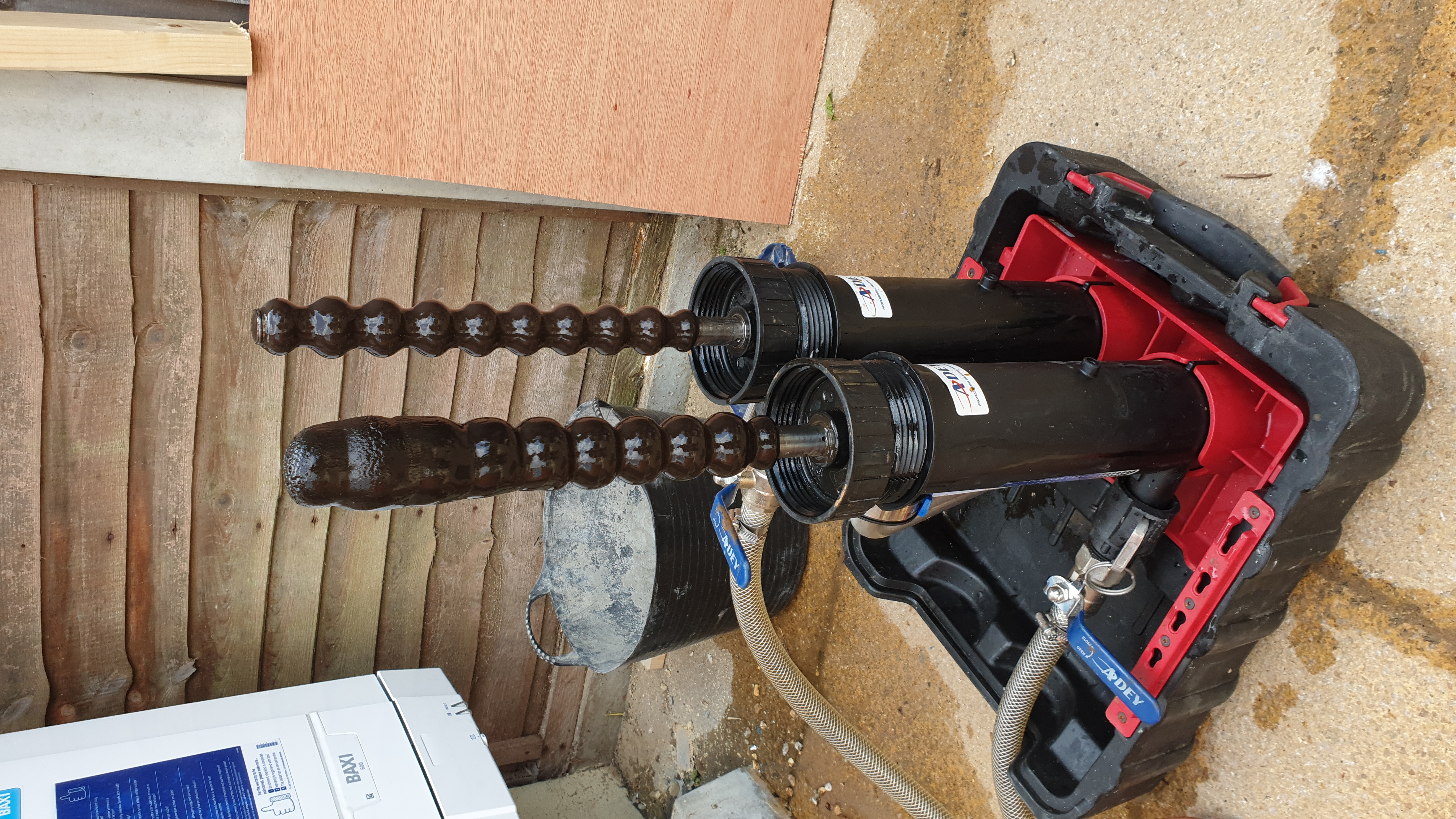 Professional drain cleaning jetting machine with coiled high-pressure hoses set up outdoors on wooden decking.