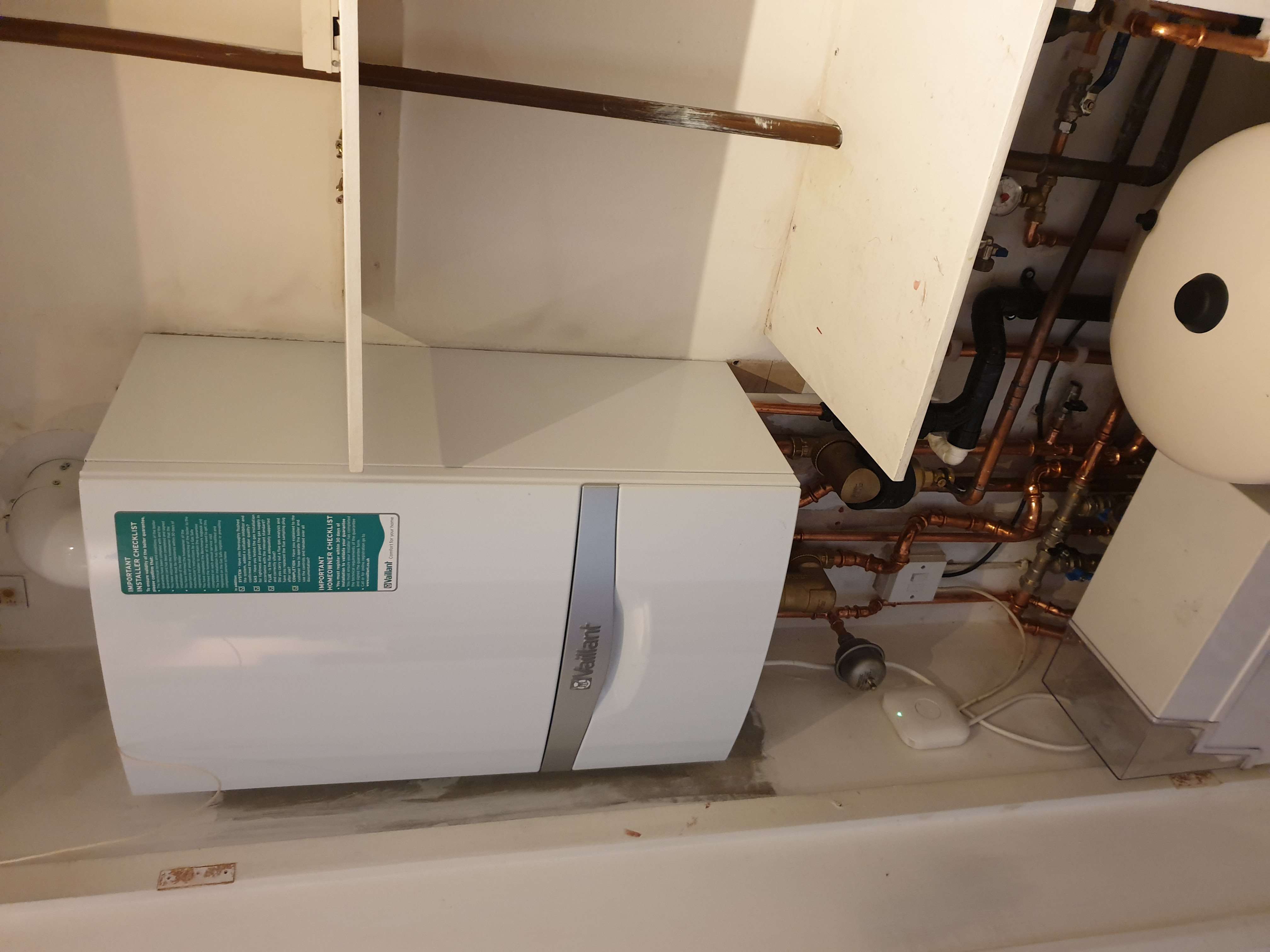 Vaillant ecoTEC boiler installed beneath stairs with white unvented hot water cylinder above and copper pipework.