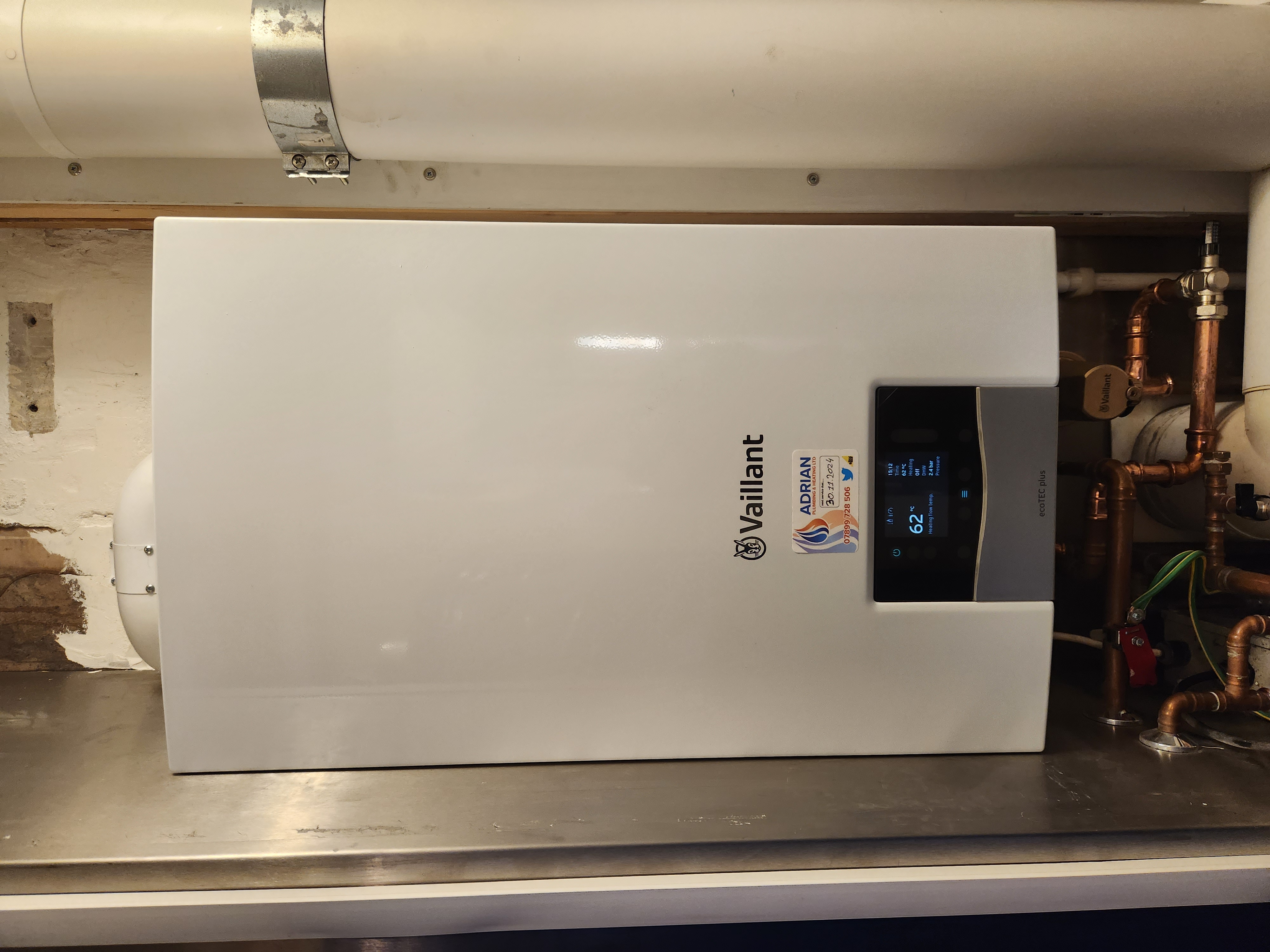 White Vaillant ecoTEC plus boiler installed within a cupboard with digital display and copper pipework.