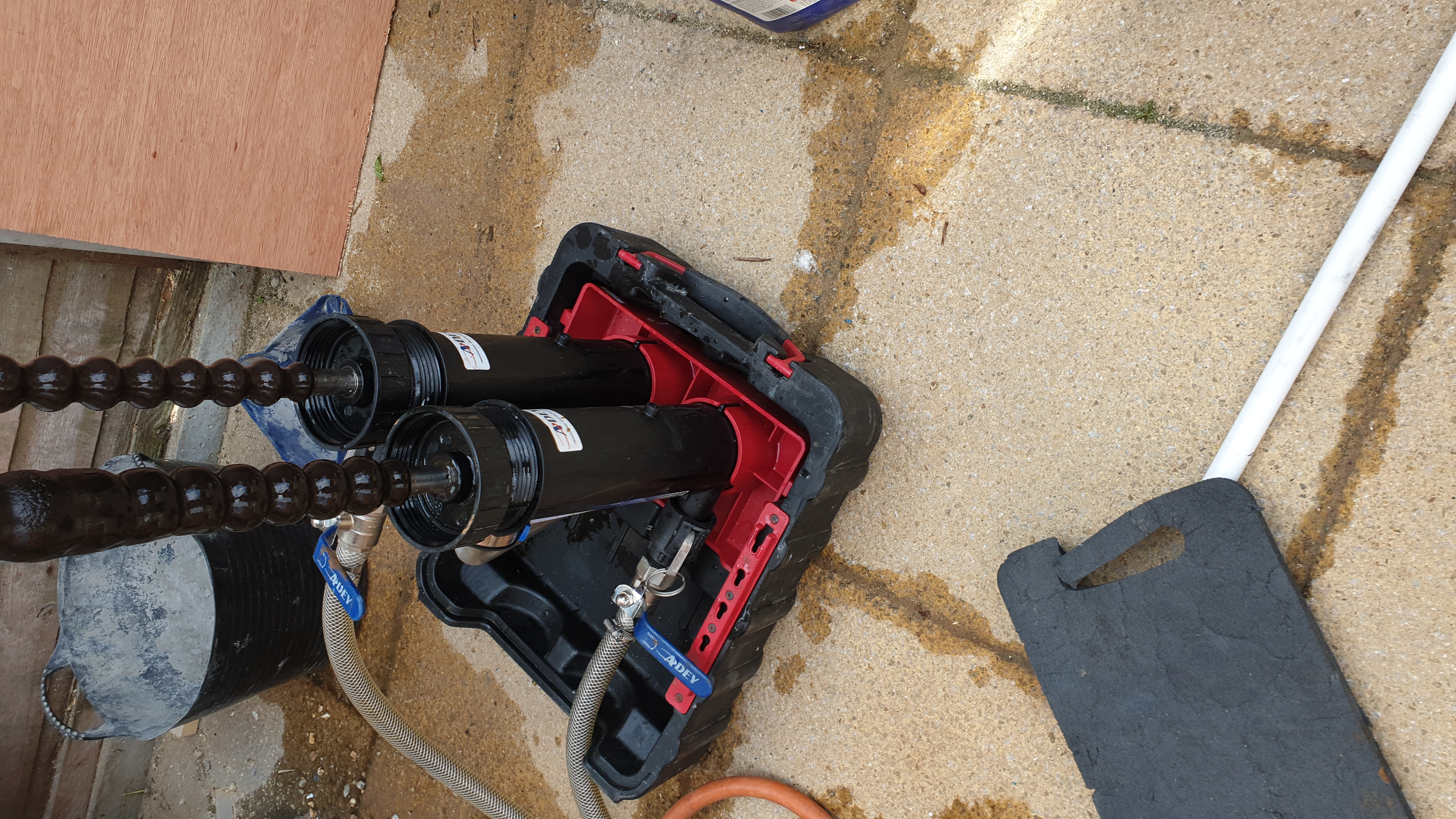 Professional drain cleaning jetting equipment with coiled high-pressure hoses set up on outdoor decking.