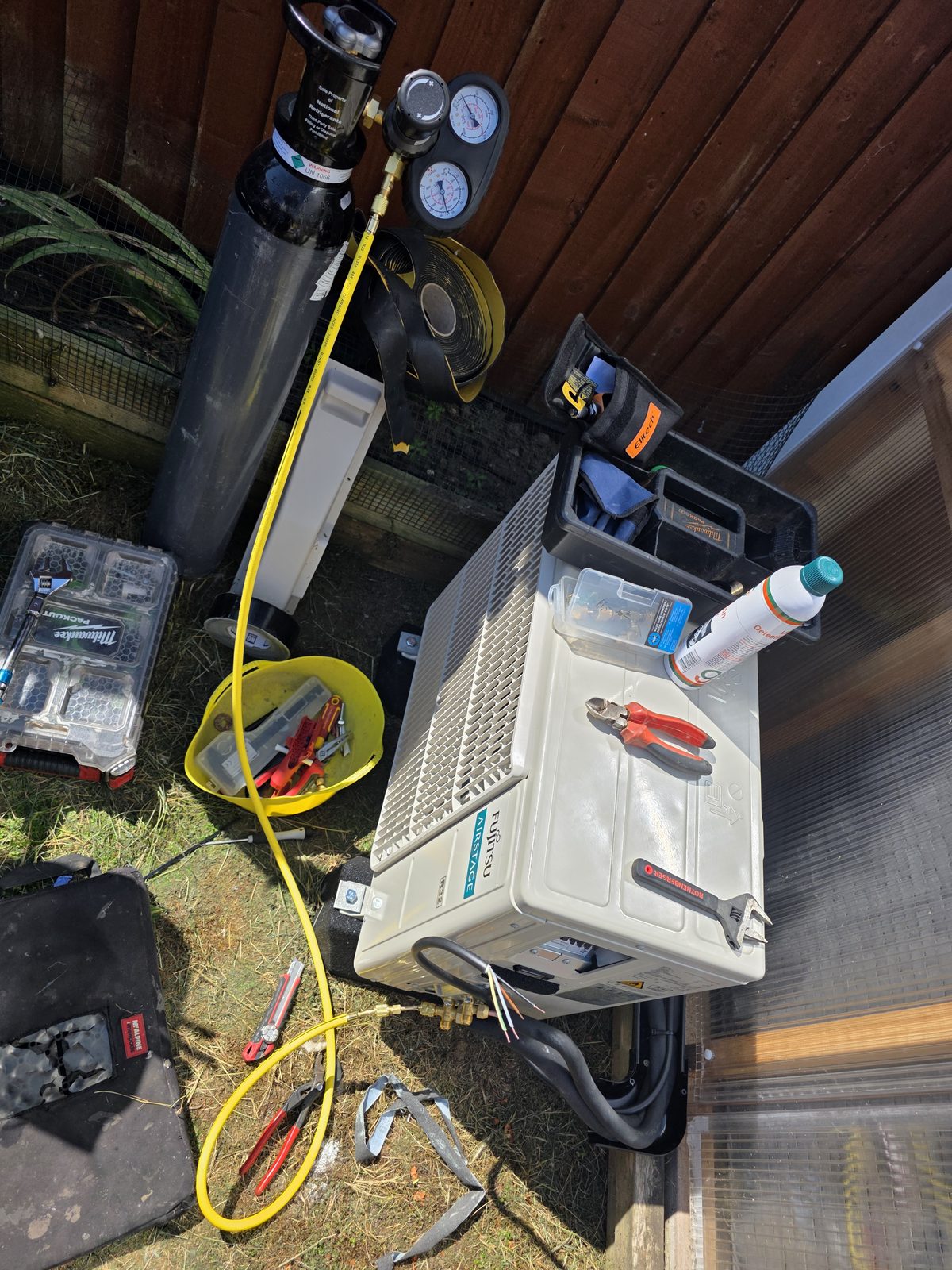 Outdoor Fujitsu air conditioning unit during installation with tools and equipment.