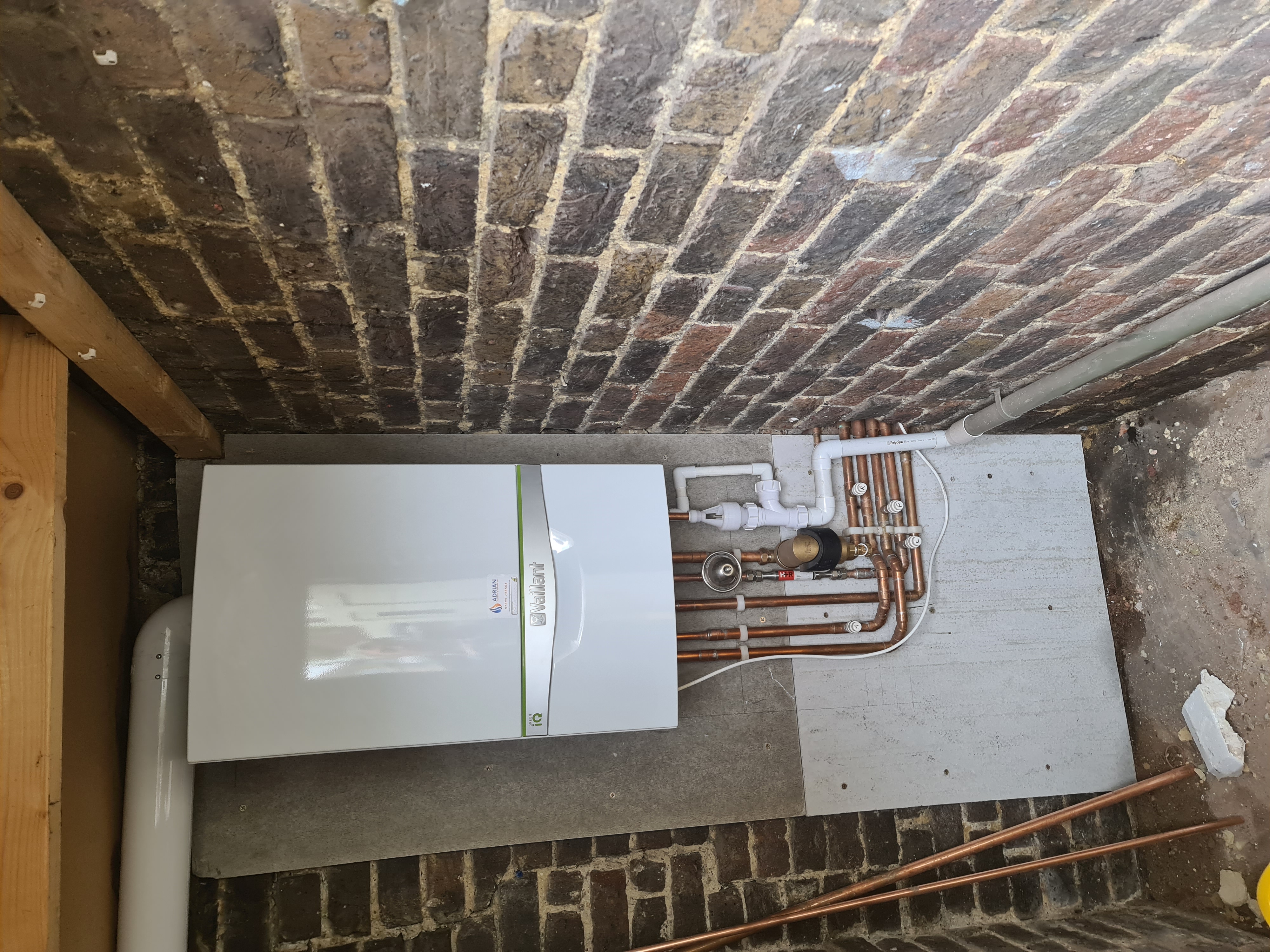 Vaillant ecoTEC boiler installed on an exposed brick wall with neatly arranged copper pipework and system components.