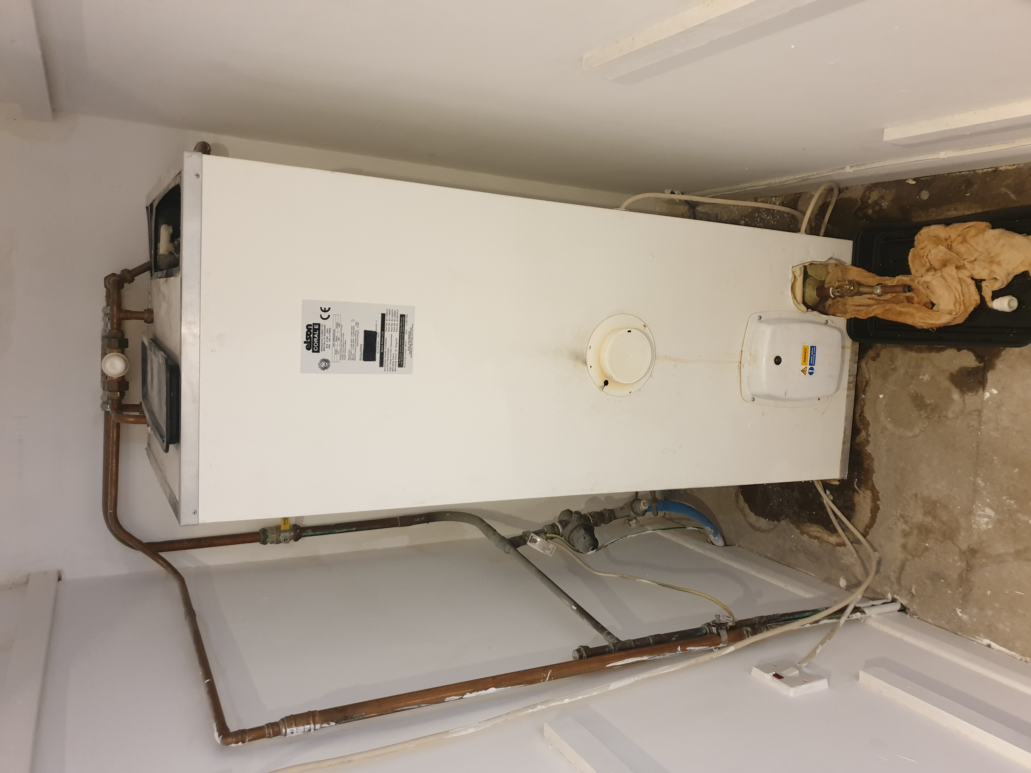 White Elson Coral boiler unit wall-mounted with exposed copper pipework and isolation valves.