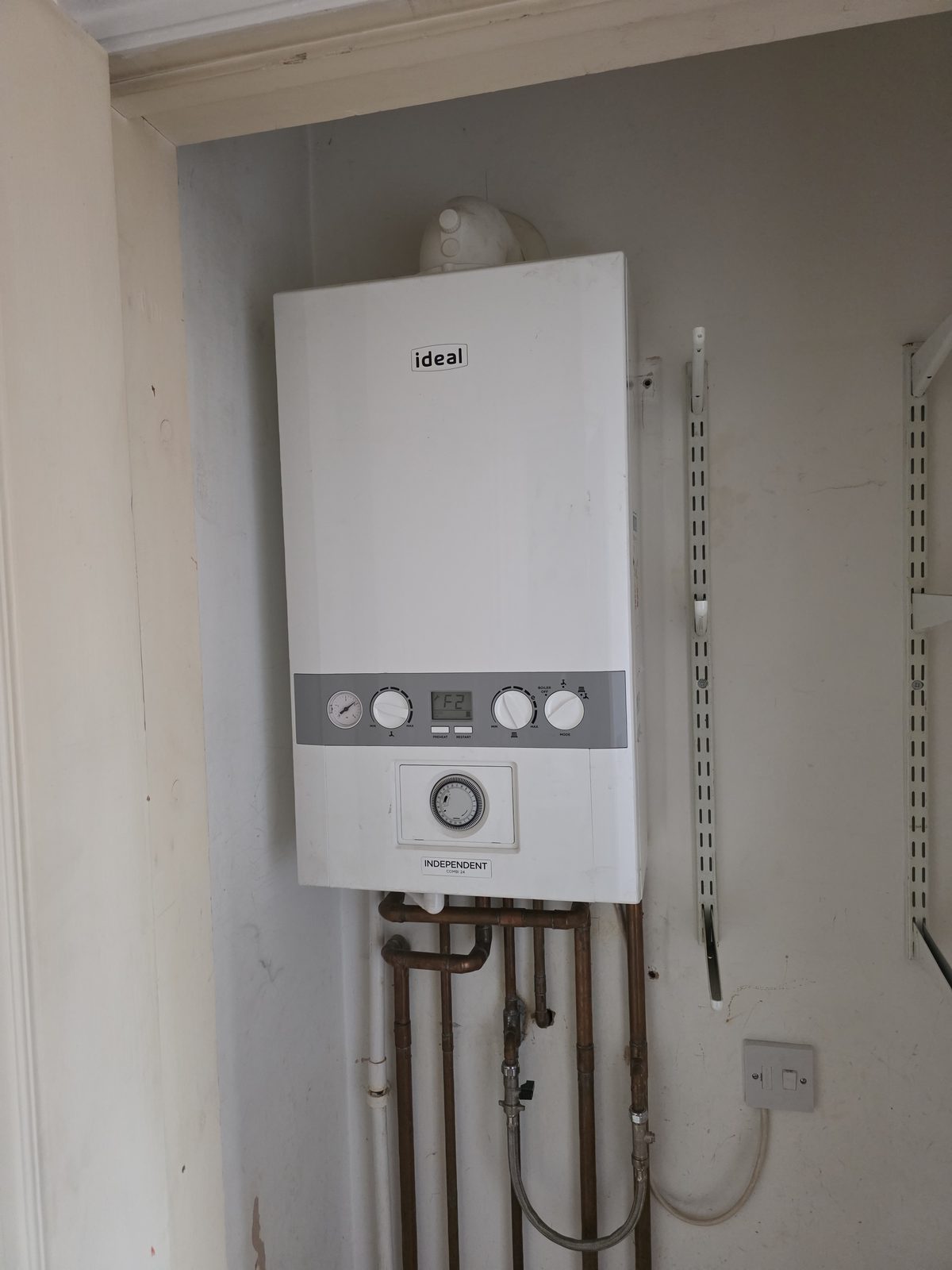 Ideal boiler installed in a utility cupboard with exposed copper pipework.