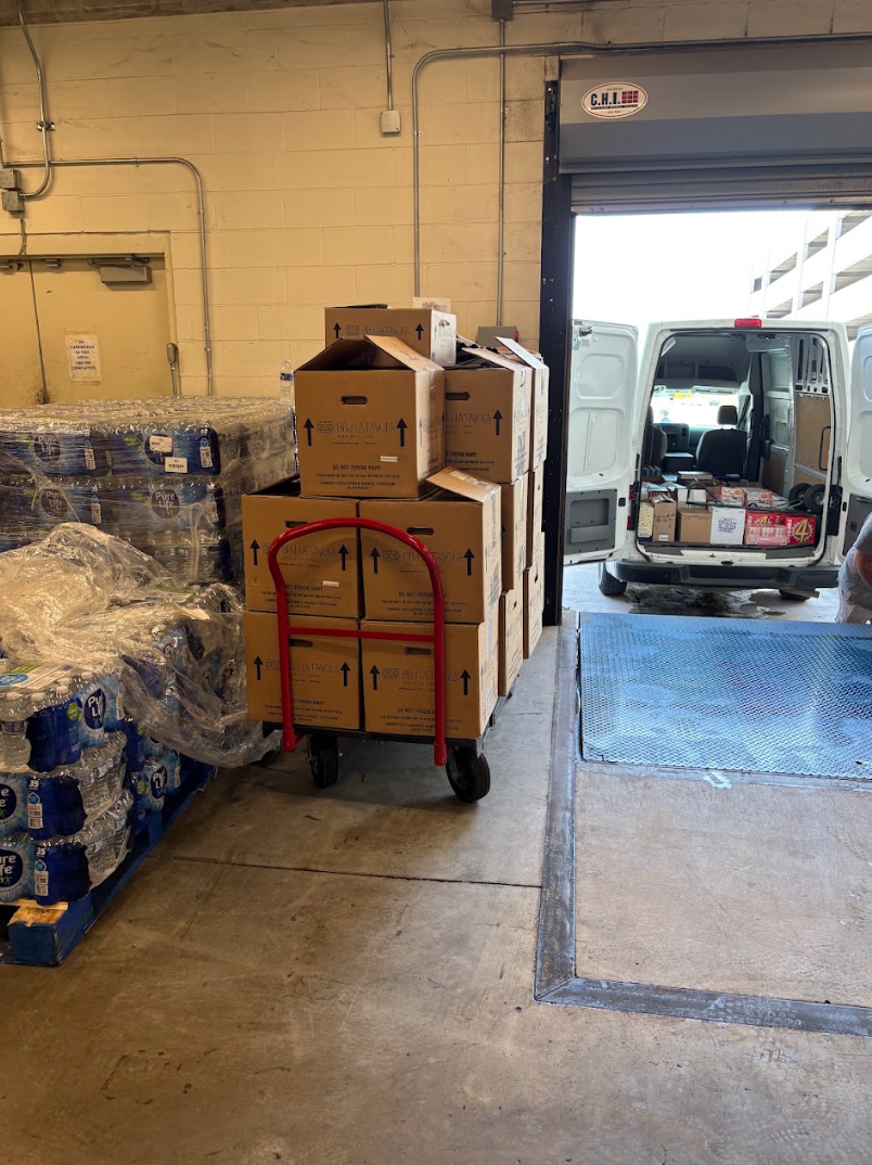 Loading dock with boxes, water pallets, and BTS van being stocked for an event delivery run