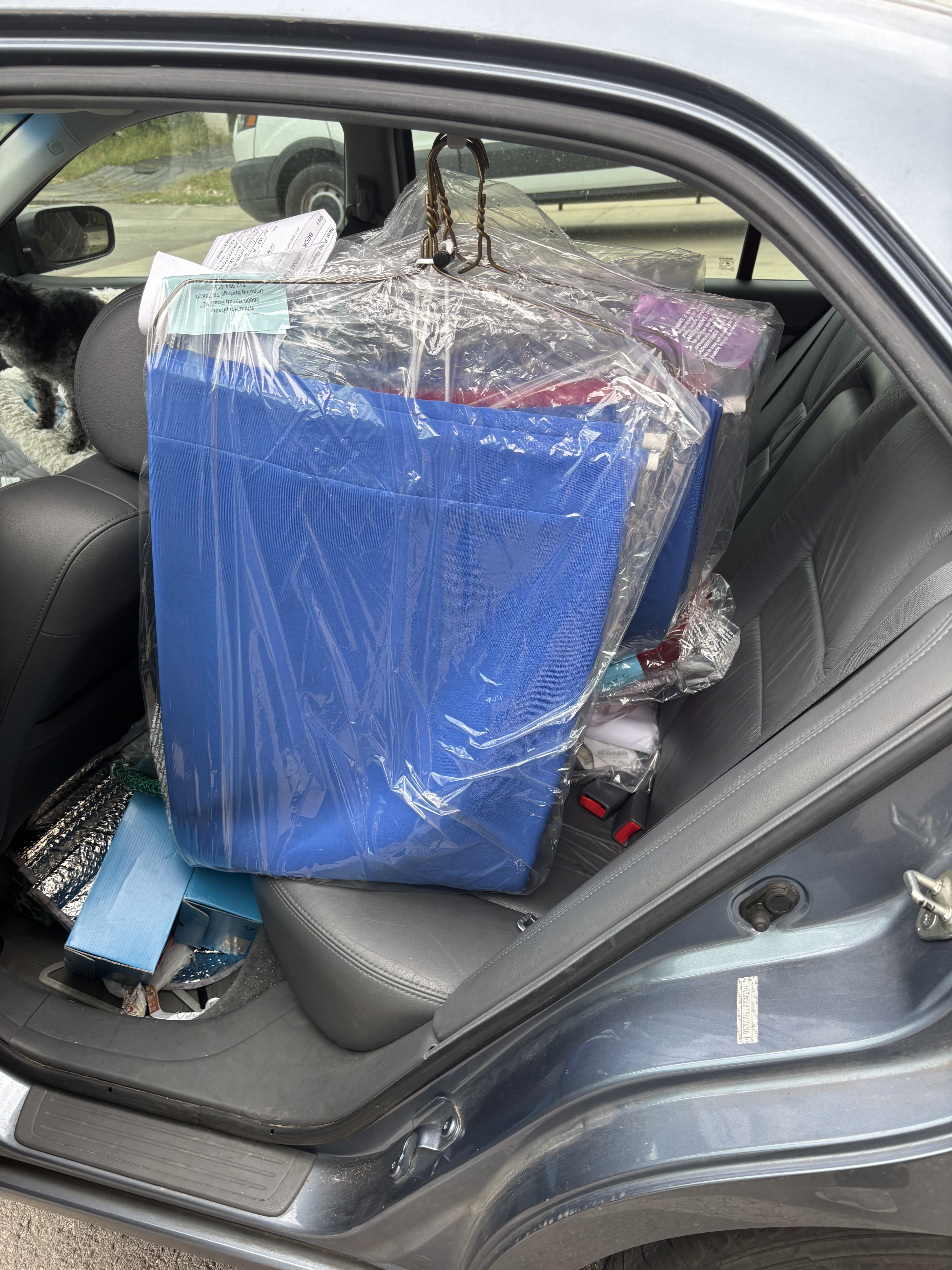 Car loaded with hanging garments, wrapped gifts, and supplies for an event