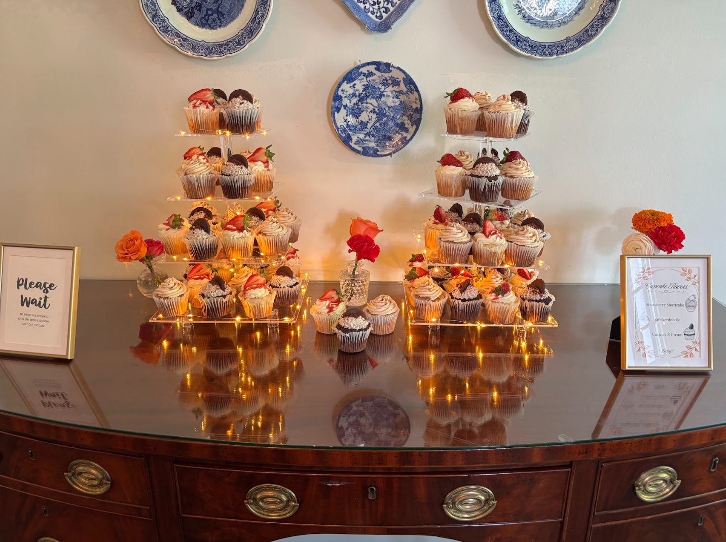 Beautiful cupcake dessert display with strawberry toppings and fairy lights on vintage sideboard for celebration