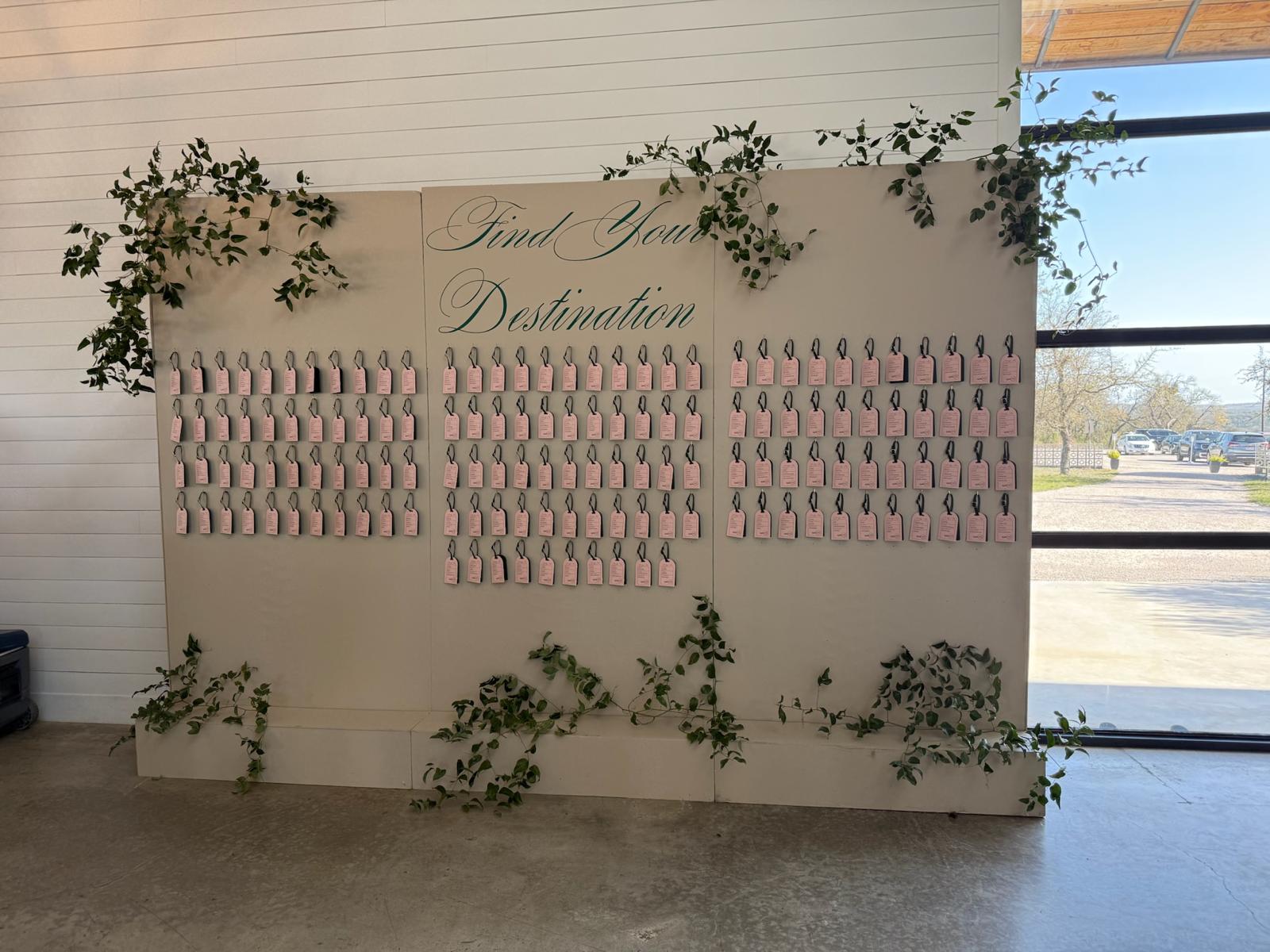 Custom seating chart display with "Find Your Destination" lettering and pink escort cards arranged for guests