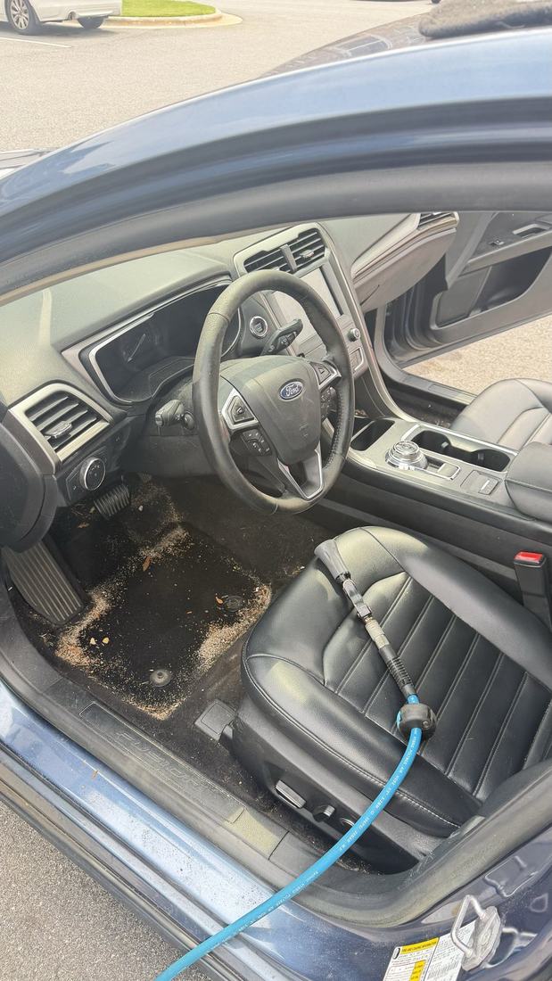 Ford Fusion interior during a deep clean with the extractor line running into the cabin