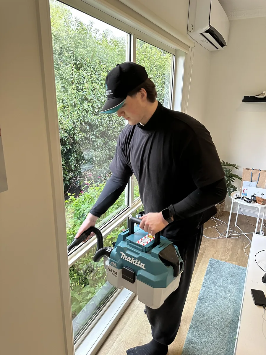 Technician vacuuming window tracks inside a Melbourne home