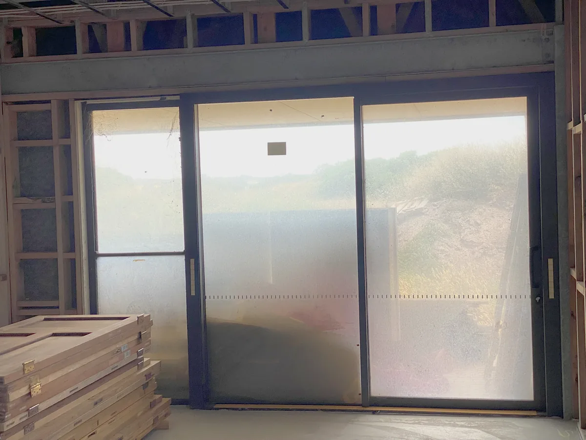 Timber framed new build with glazing installed and materials stacked inside