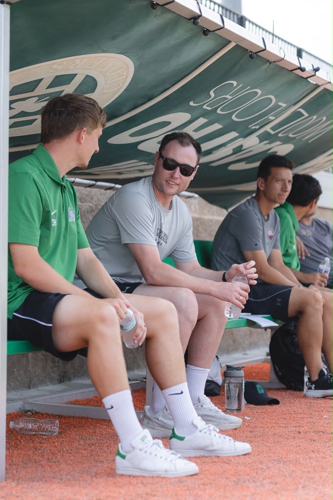 Coach Zack Hargreaves connecting with university coaches on bench