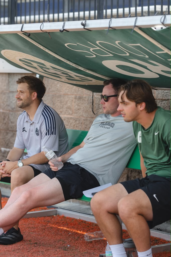 College coaches and scouts evaluating players from dugout bench