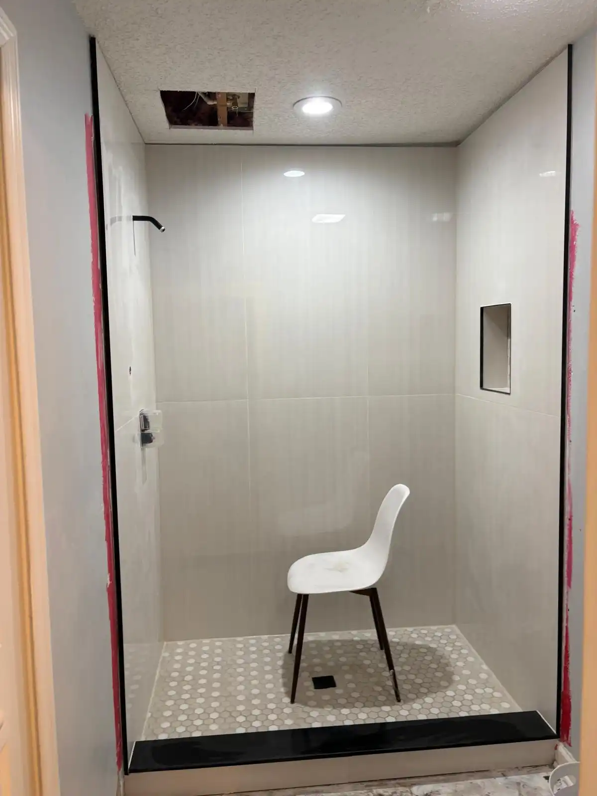 Completed bathroom renovation by Home Doctors of Jax: white subway tile walls, hexagon tile floor, glass enclosure, and built-in niche