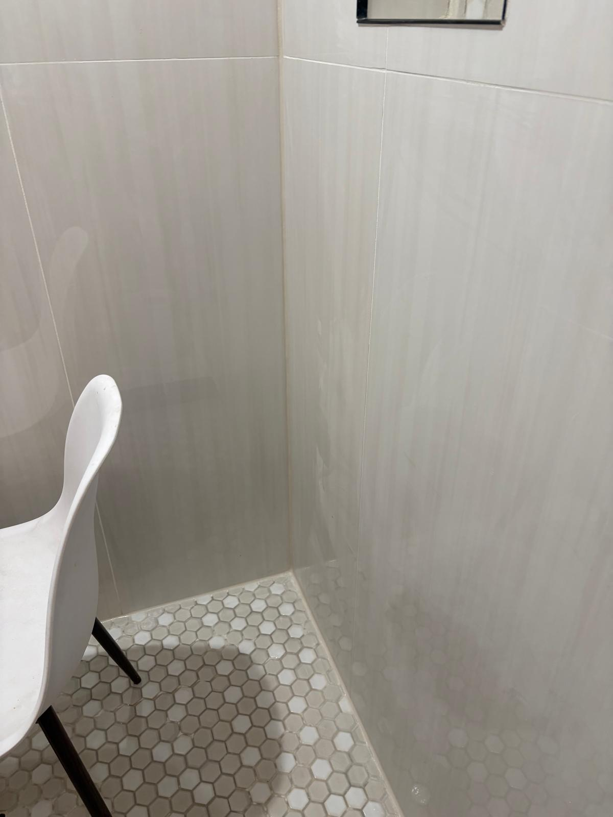 Finished shower with new white subway tile and hexagon mosaic floor after repair