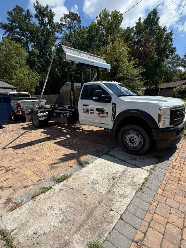 White JAX Dumpsters roll-off truck with lift system parked on brick driveway