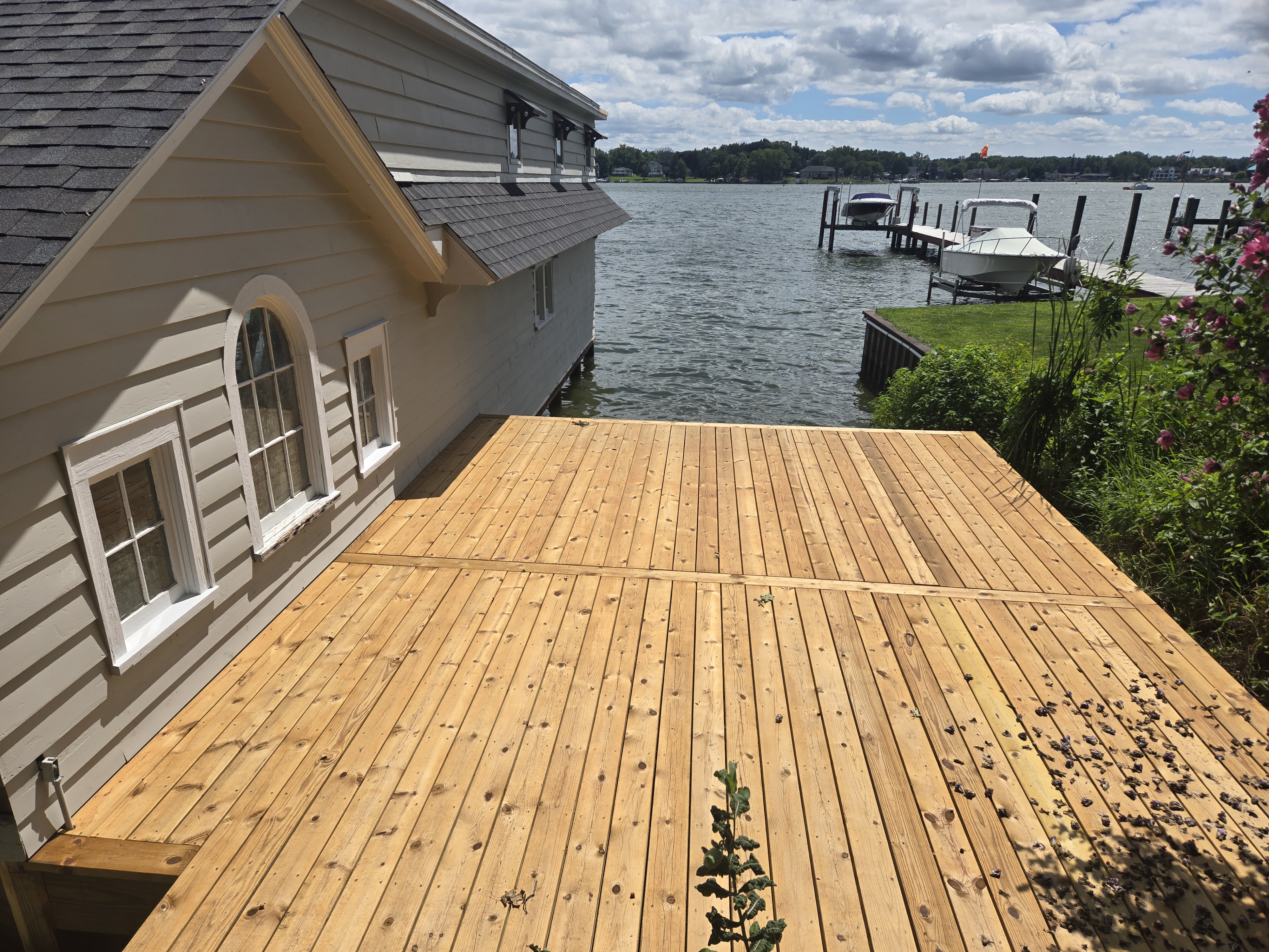 Custom wooden waterfront deck beside boathouse