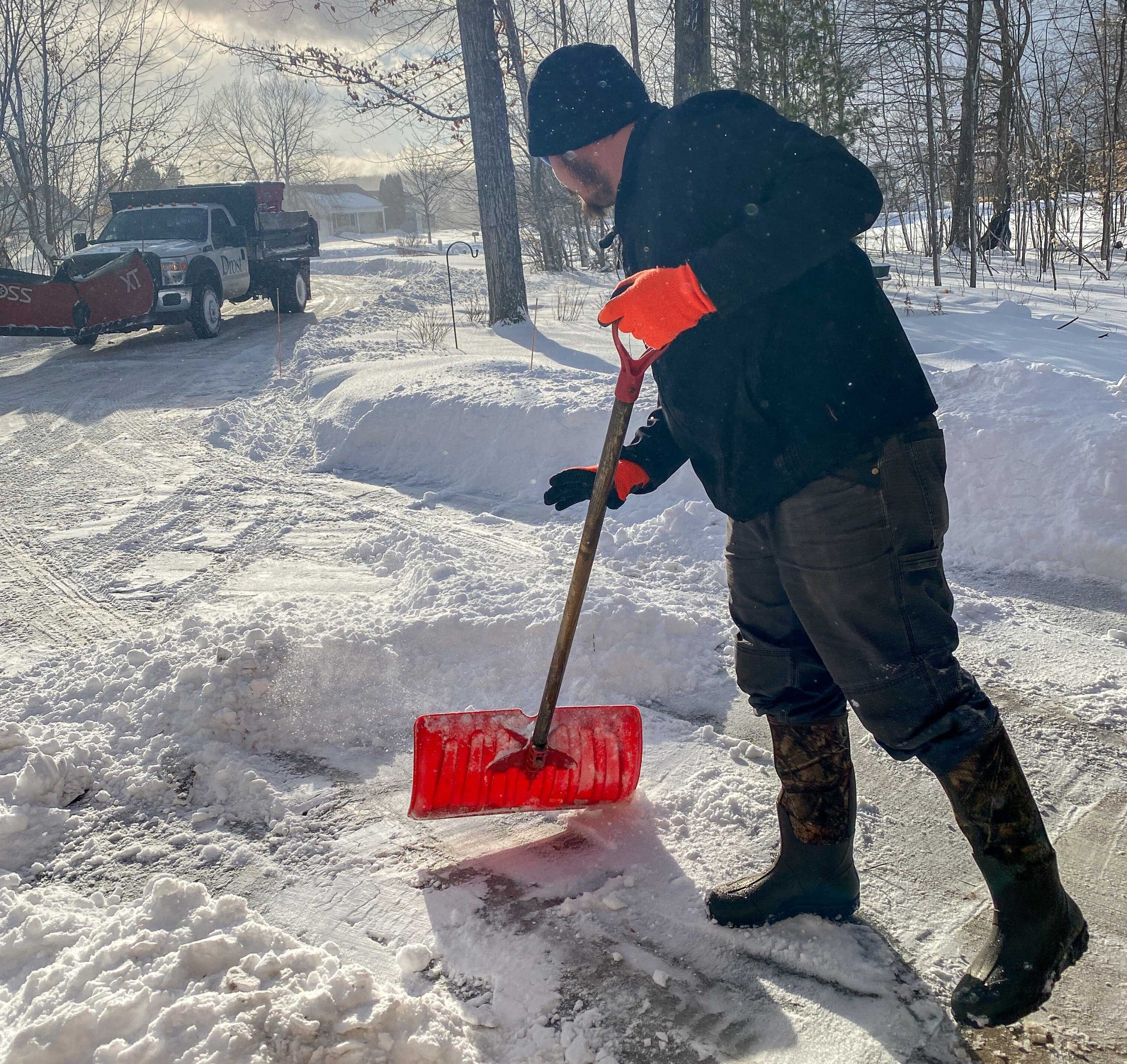 Grow Luck crew member clearing walkways and public sidewalk during winter storm