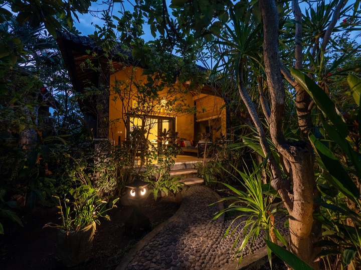 Exterior del bungalow de noche con iluminación cálida y sendero de piedras — Pondok Tirta Homestay Amed Bali