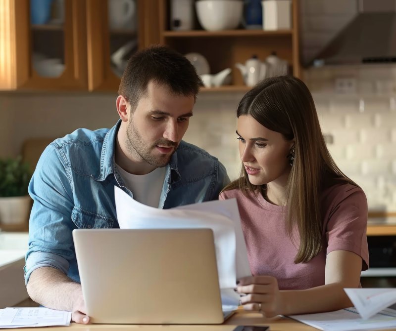 Couple reviewing immigration bond paperwork and laptop together