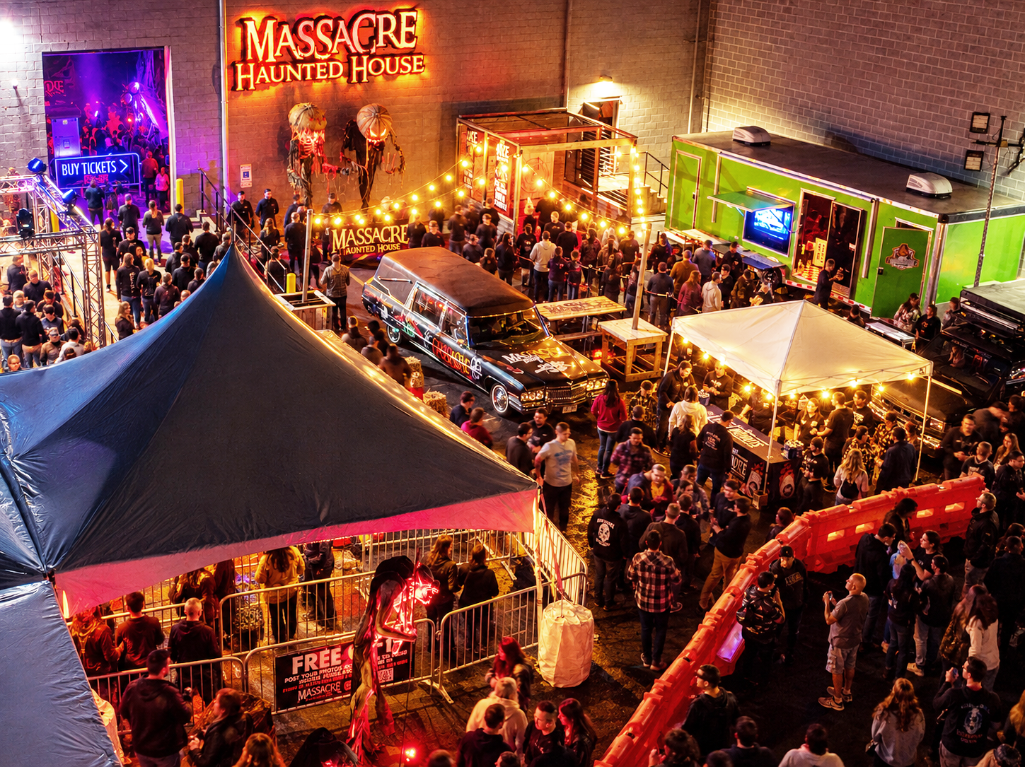 Massacre Midway outdoor festival courtyard with hearse and crowd at Massacre Haunted House