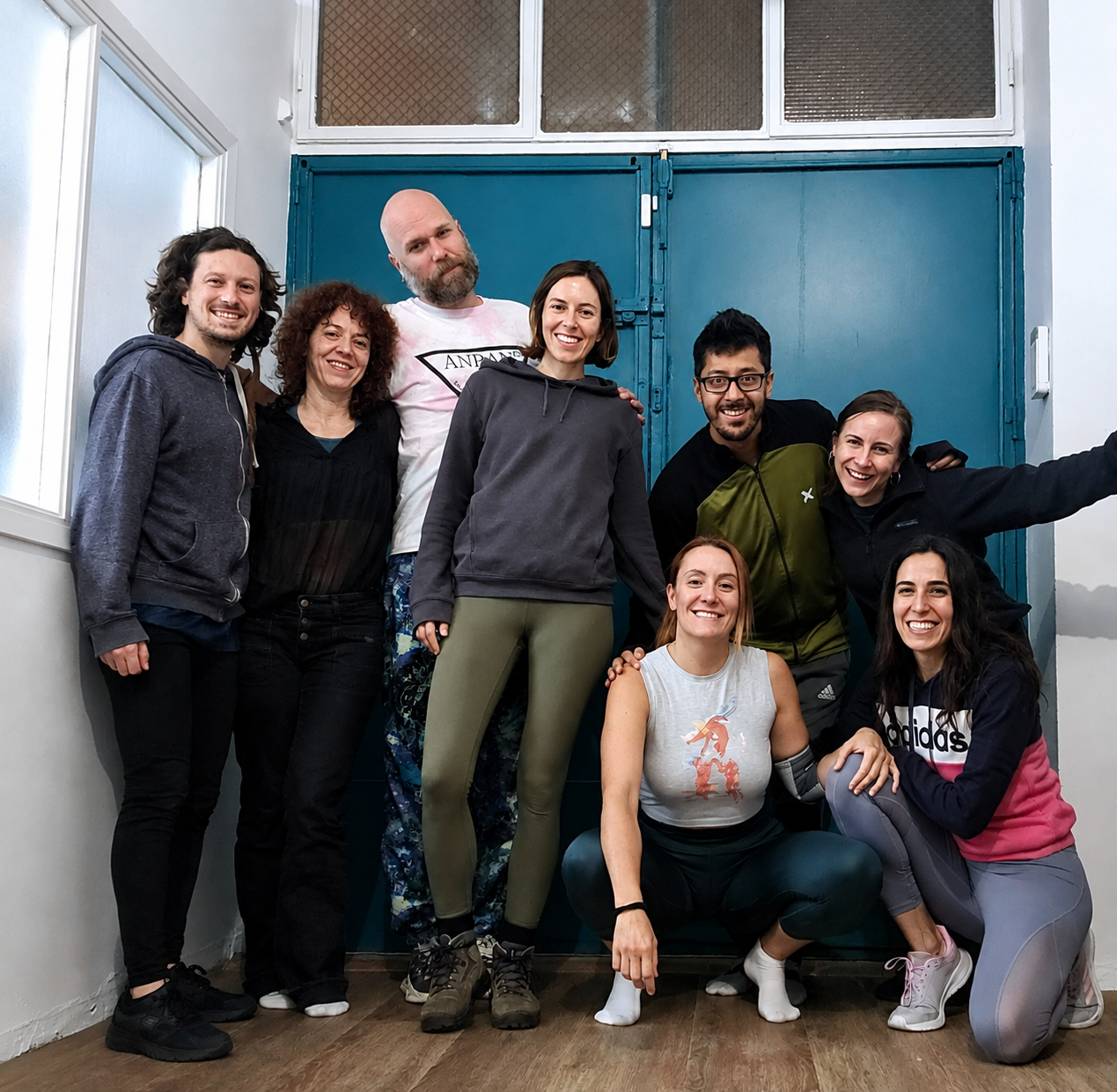Comunidad Akrobatia — grupo sonriente frente a puerta azul