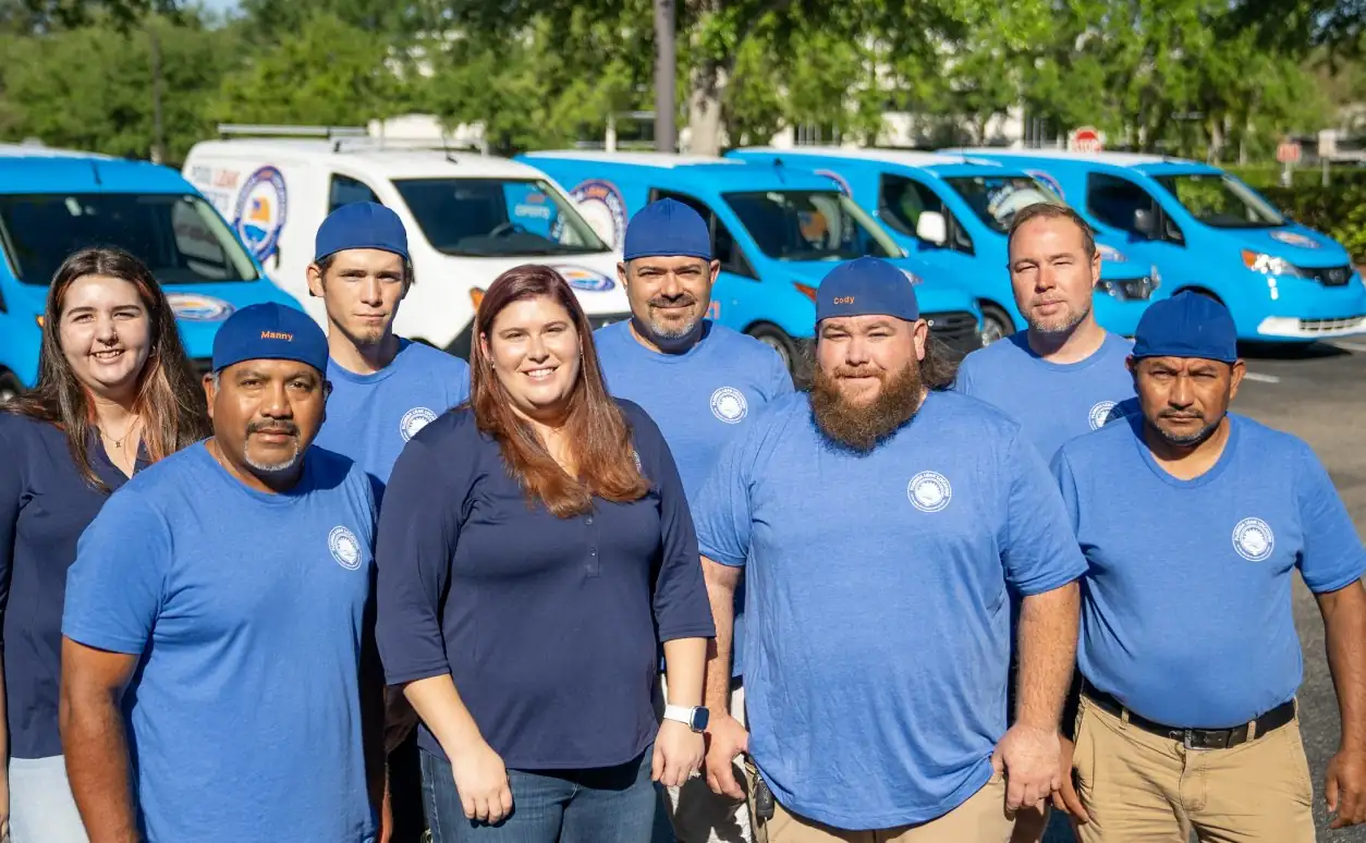 The Florida Leak Locators team in matching blue shirts standing in front of company vans
