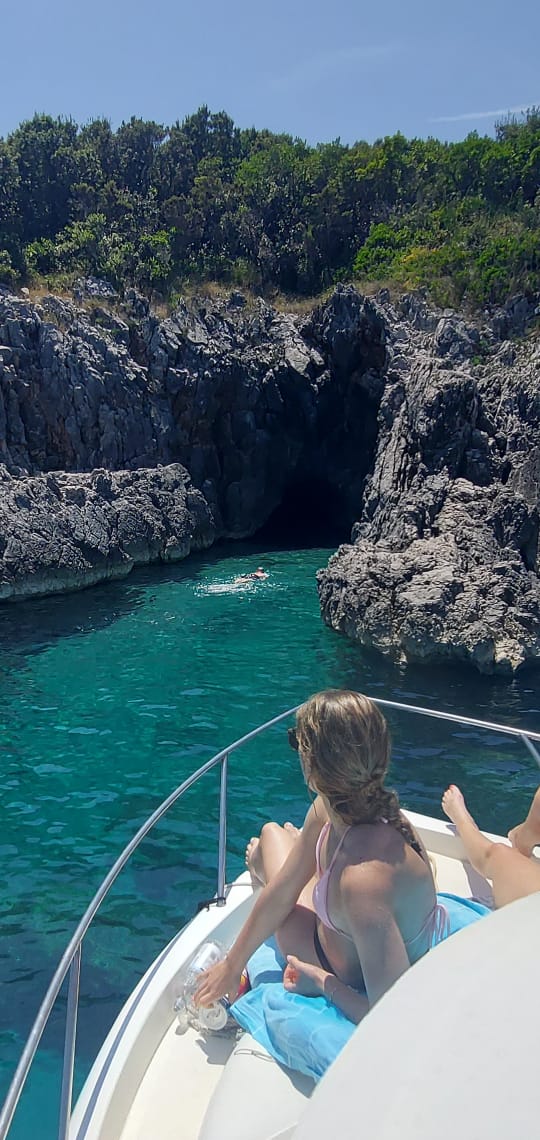 Guest relaxing on deck with coastal caves backdrop
