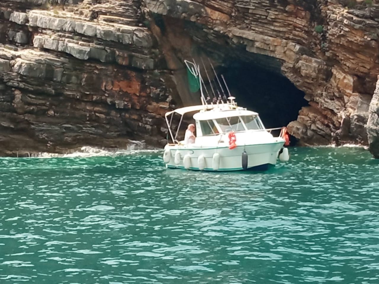 White boat entering glowing sea cave