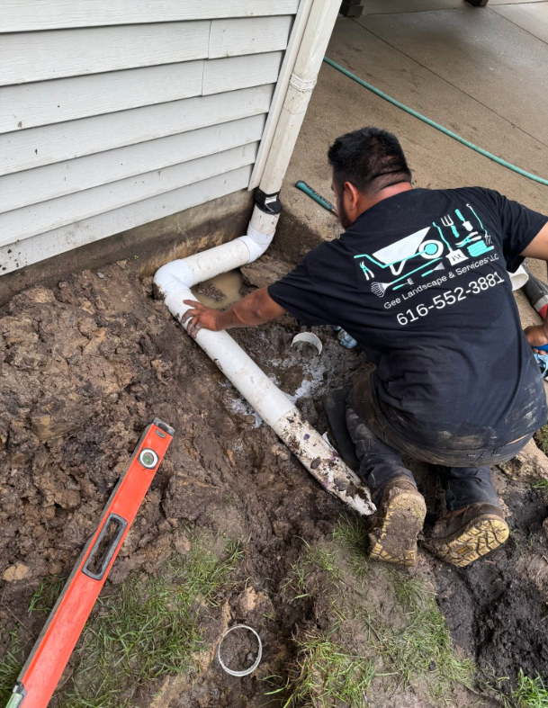 Gee Landscape & Services connecting a downspout drain pipe at a West Michigan residential property