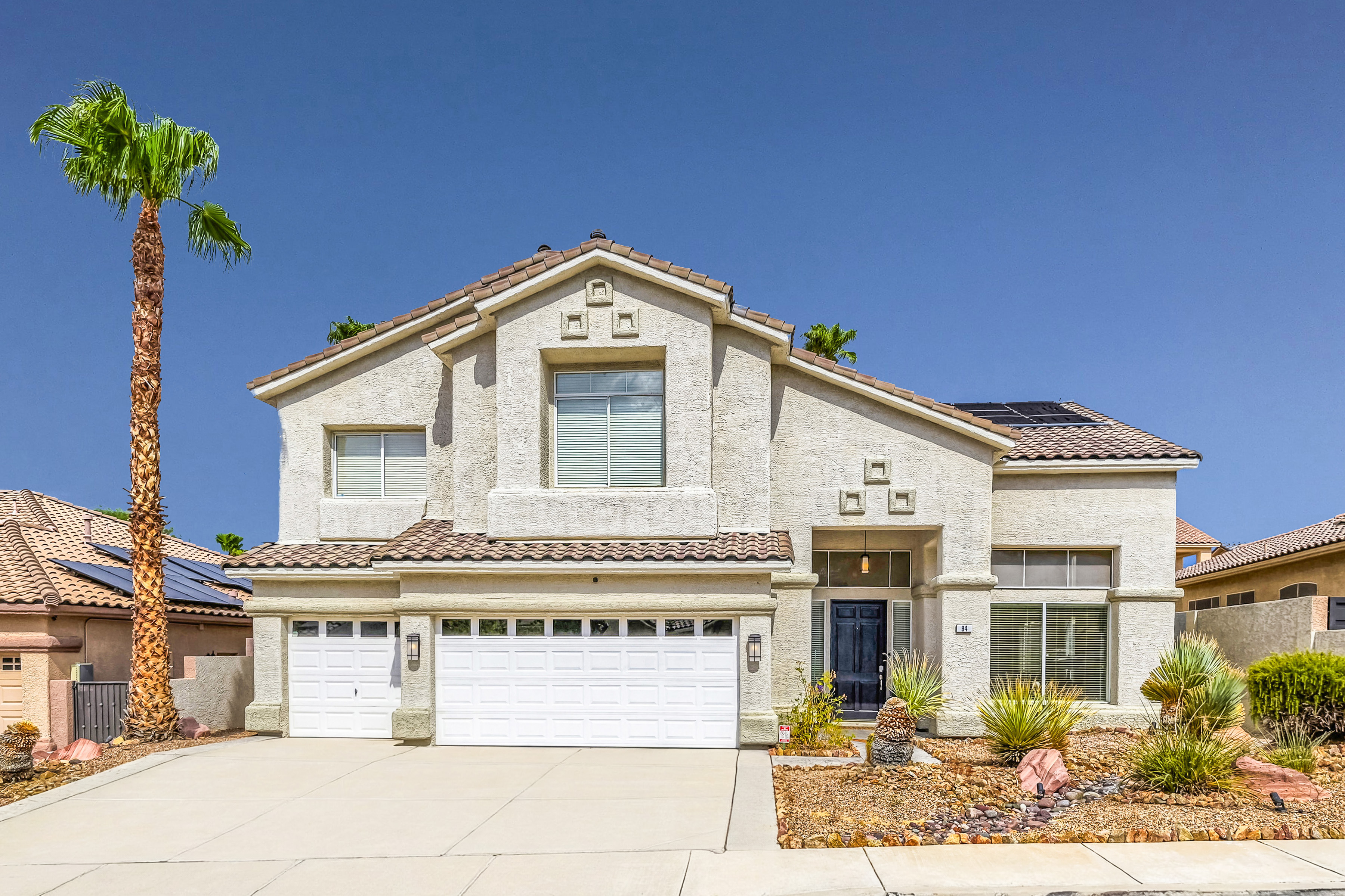 Exterior of 94 Shepherd Mesa Ct. in Henderson Nevada showing two-story home with tile roof, palm tree and three-car garage