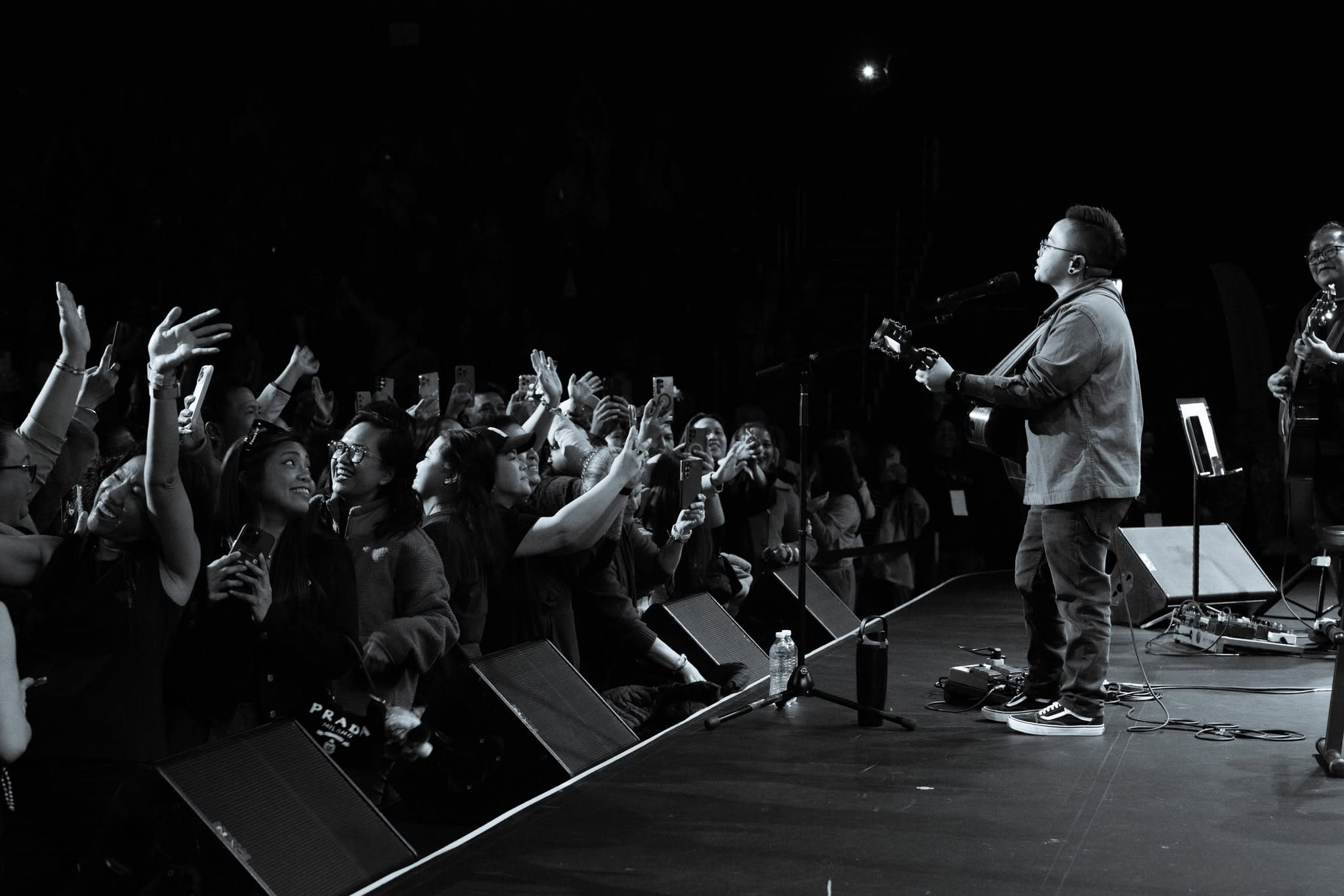 Ice Seguerra performing intimately with acoustic guitar on stage, connecting with singing fans in the front row during the Pagdating ng Panahon 25th Anniversary Tour.
