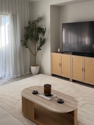 Lounge room with timber coffee table, woven media console and sheer curtains
