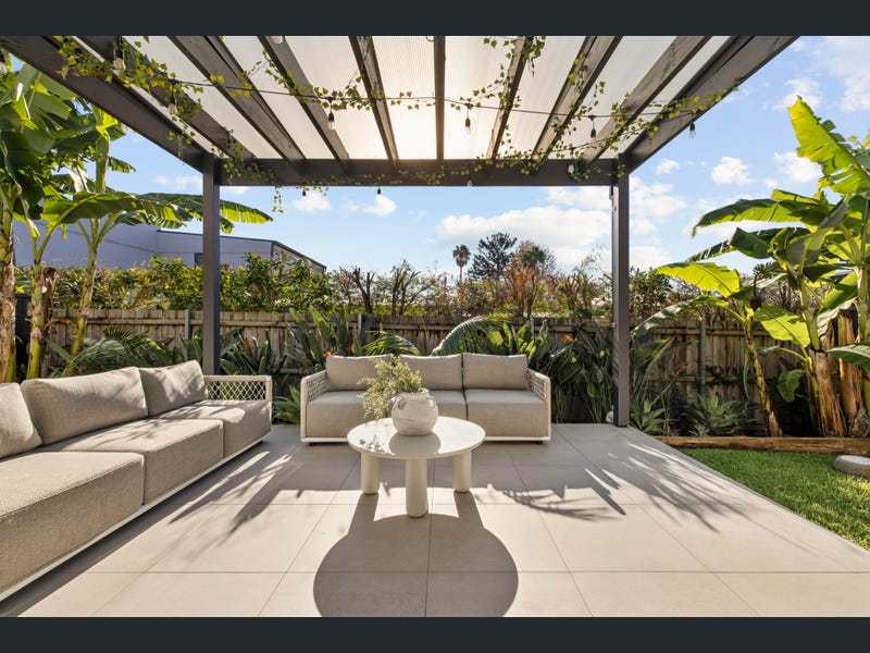 Waterfront outdoor entertaining area with pergola and lush landscaping in Huntleys Point.