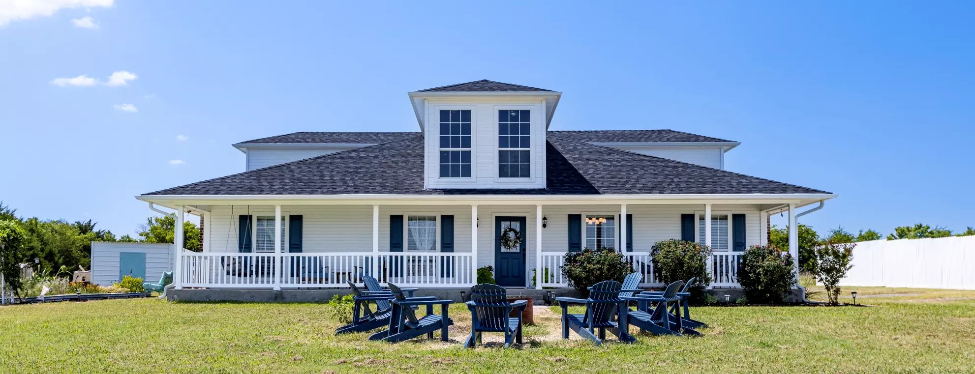 White farmhouse with wrap-around porch and outdoor seating