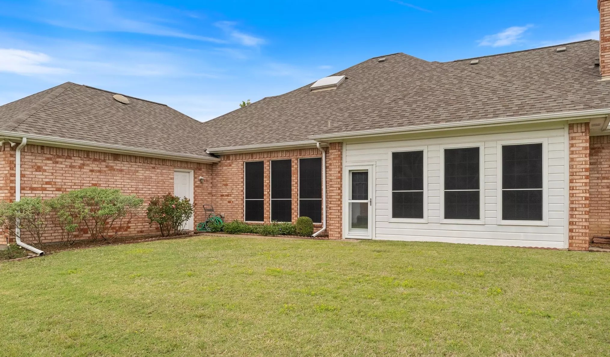 Brick home with green lawn and mature landscaping