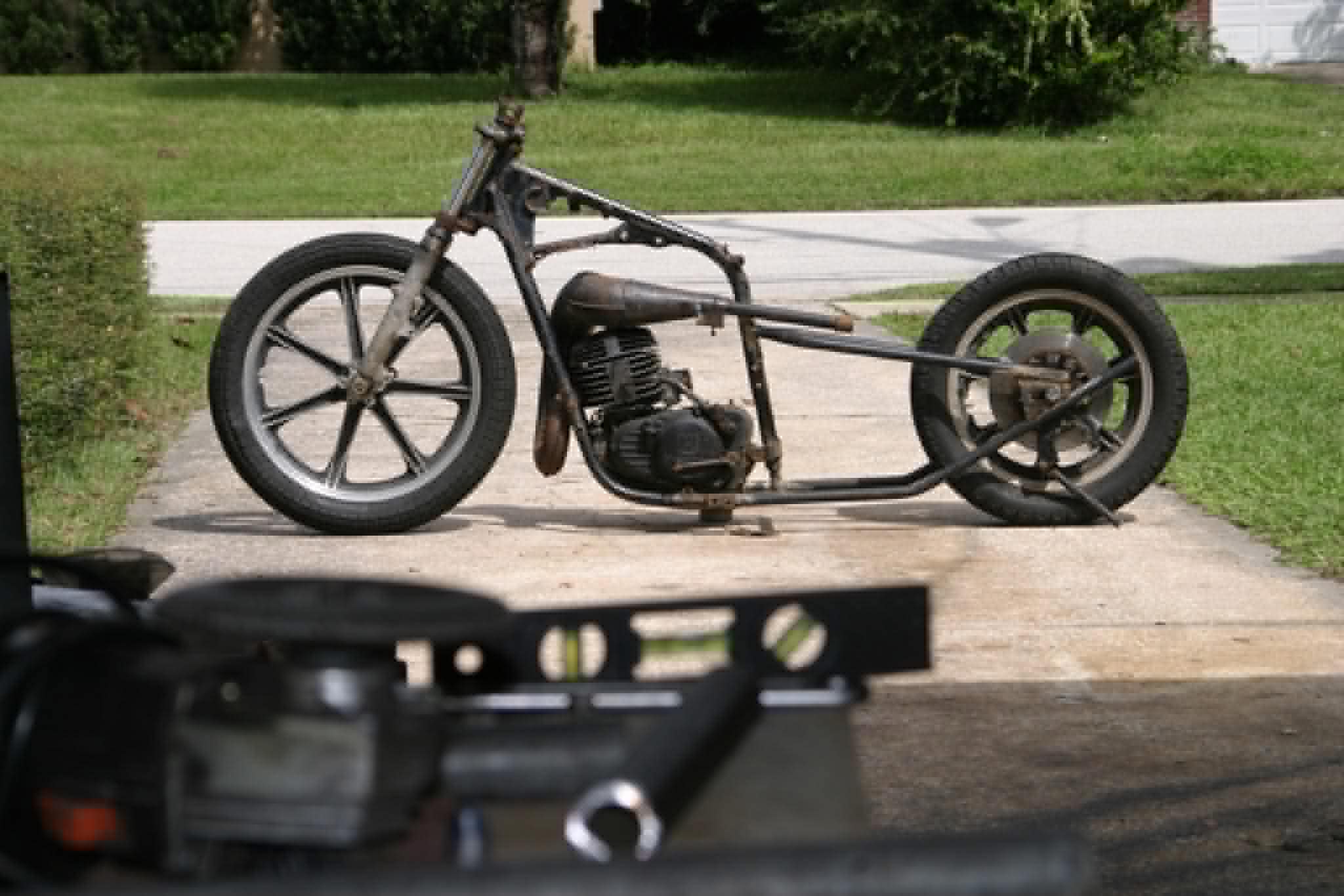 Bare motorcycle frame and engine on driveway ready for full custom rebuild by Marlito