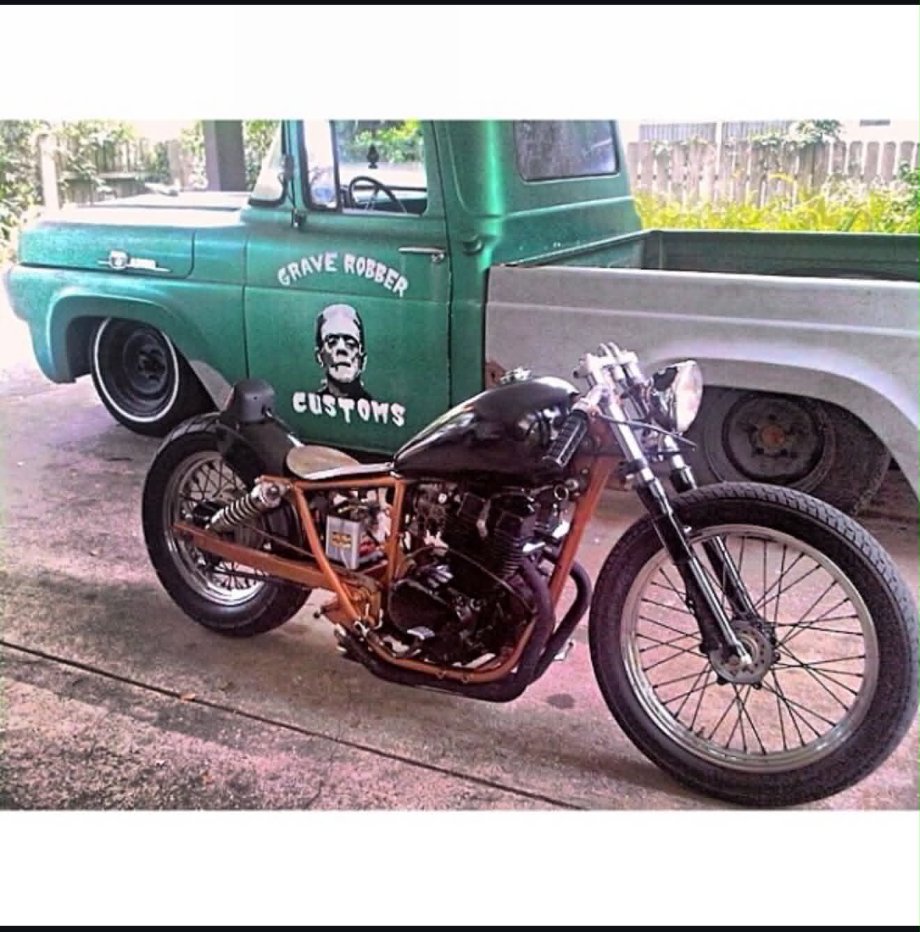 Custom orange and black bobber motorcycle built by Marlito with vintage truck backdrop